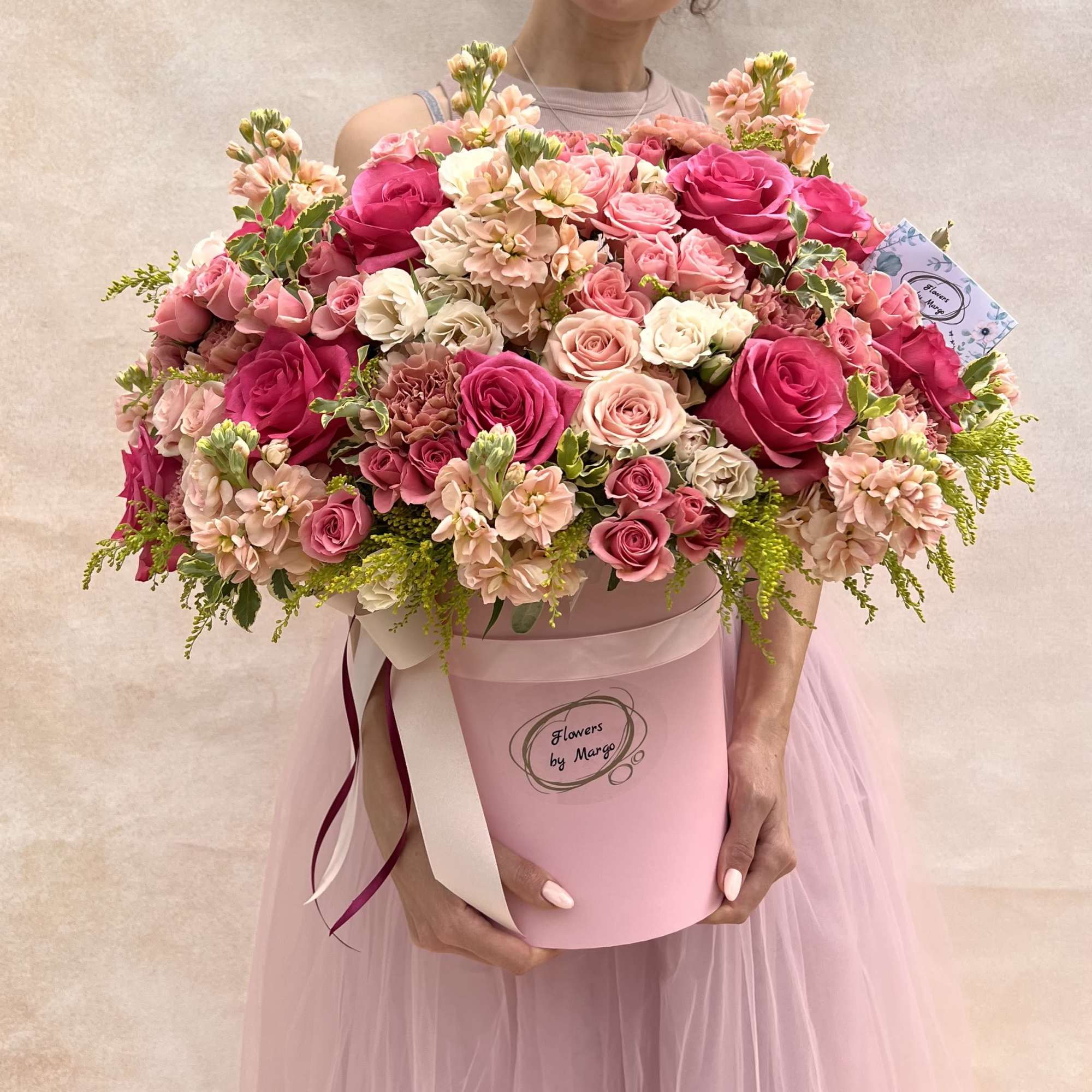 Large pink and peach rose hatbox arrangement held by a person in a pink dress