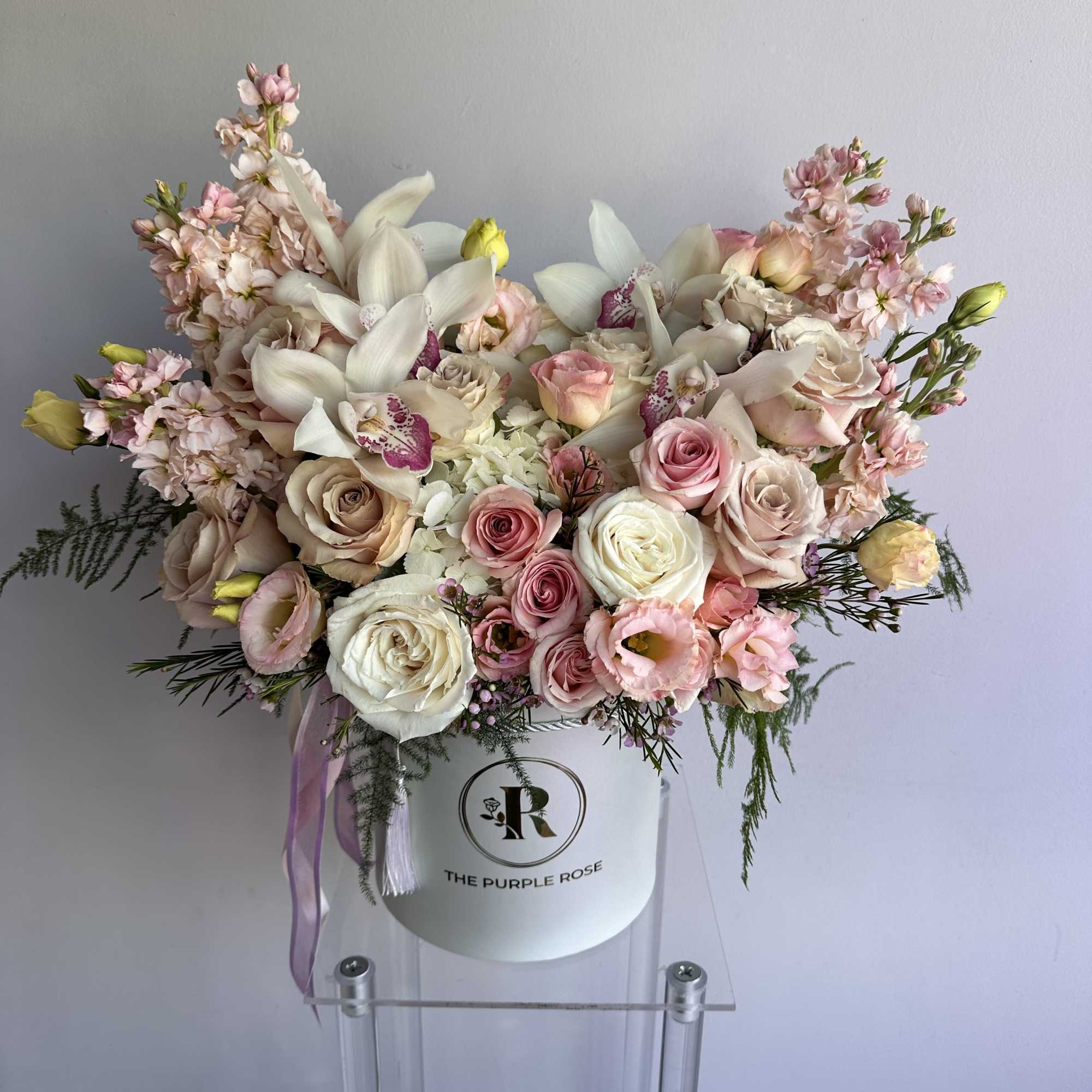 Pastel pink and white flower hatbox arrangement with roses, orchids, lisianthus, and hydrangea in a white round box.
