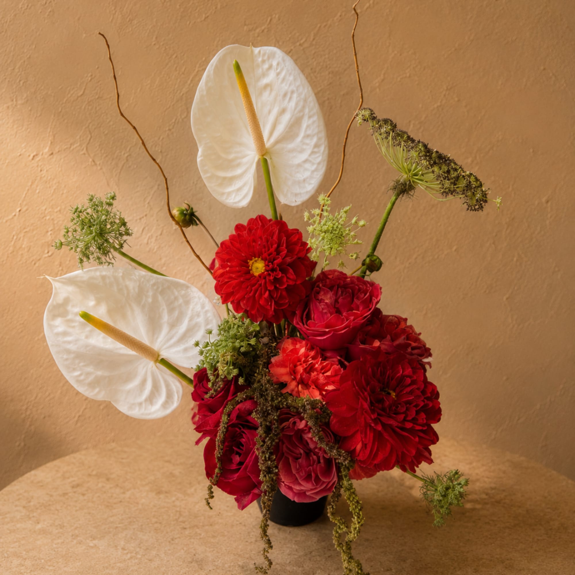 Red and white floral arrangement in a small black vase
