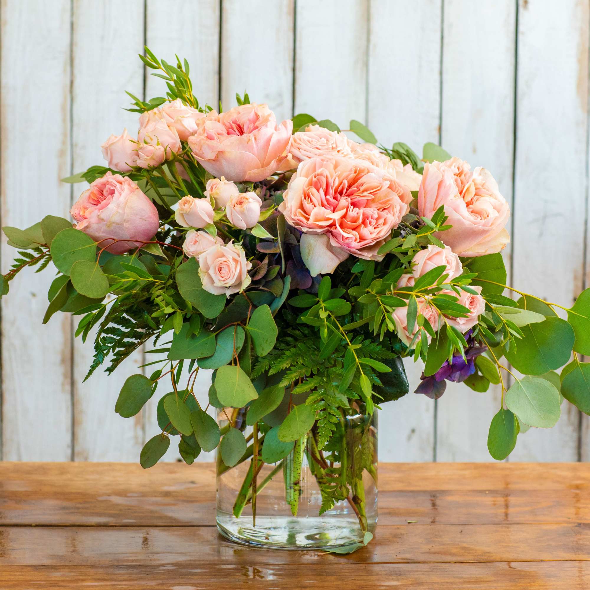 Pink roses in a clear glass vase with greenery