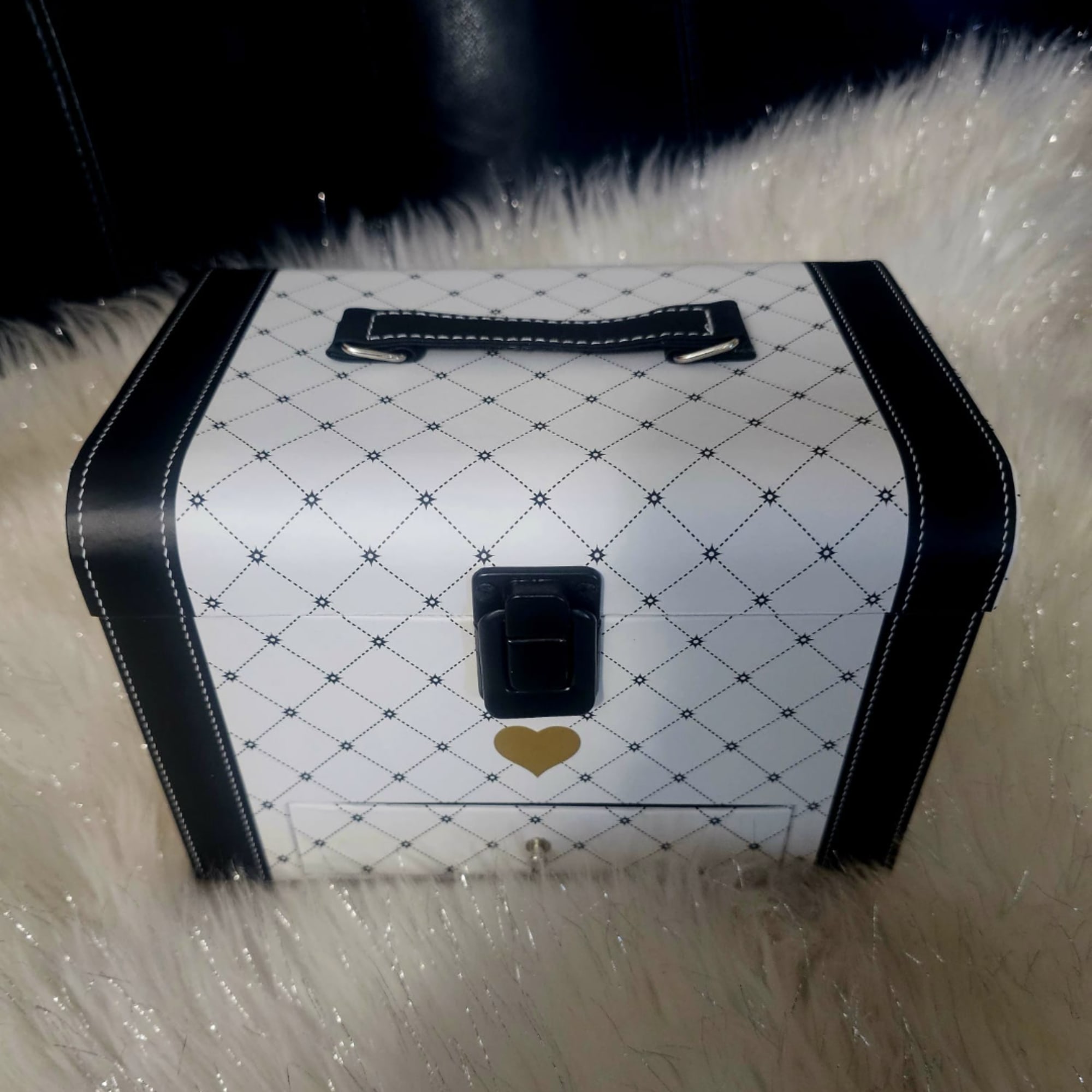 Decorative white gift box with black trim and a heart clasp