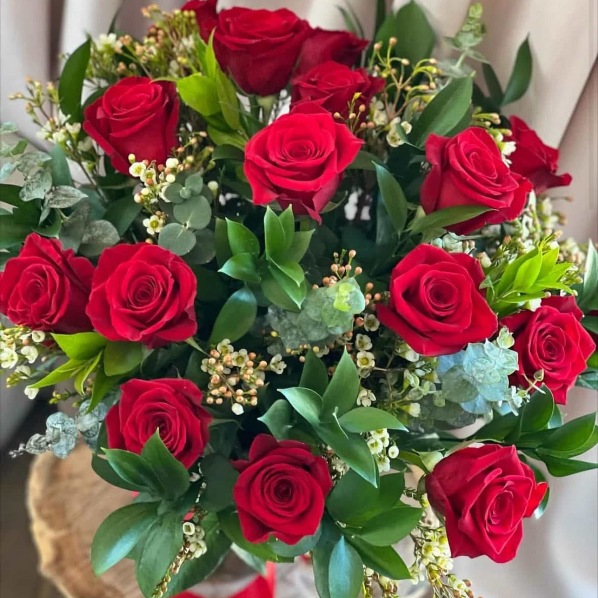 Bouquet of red roses with mixed greenery and small white filler flowers