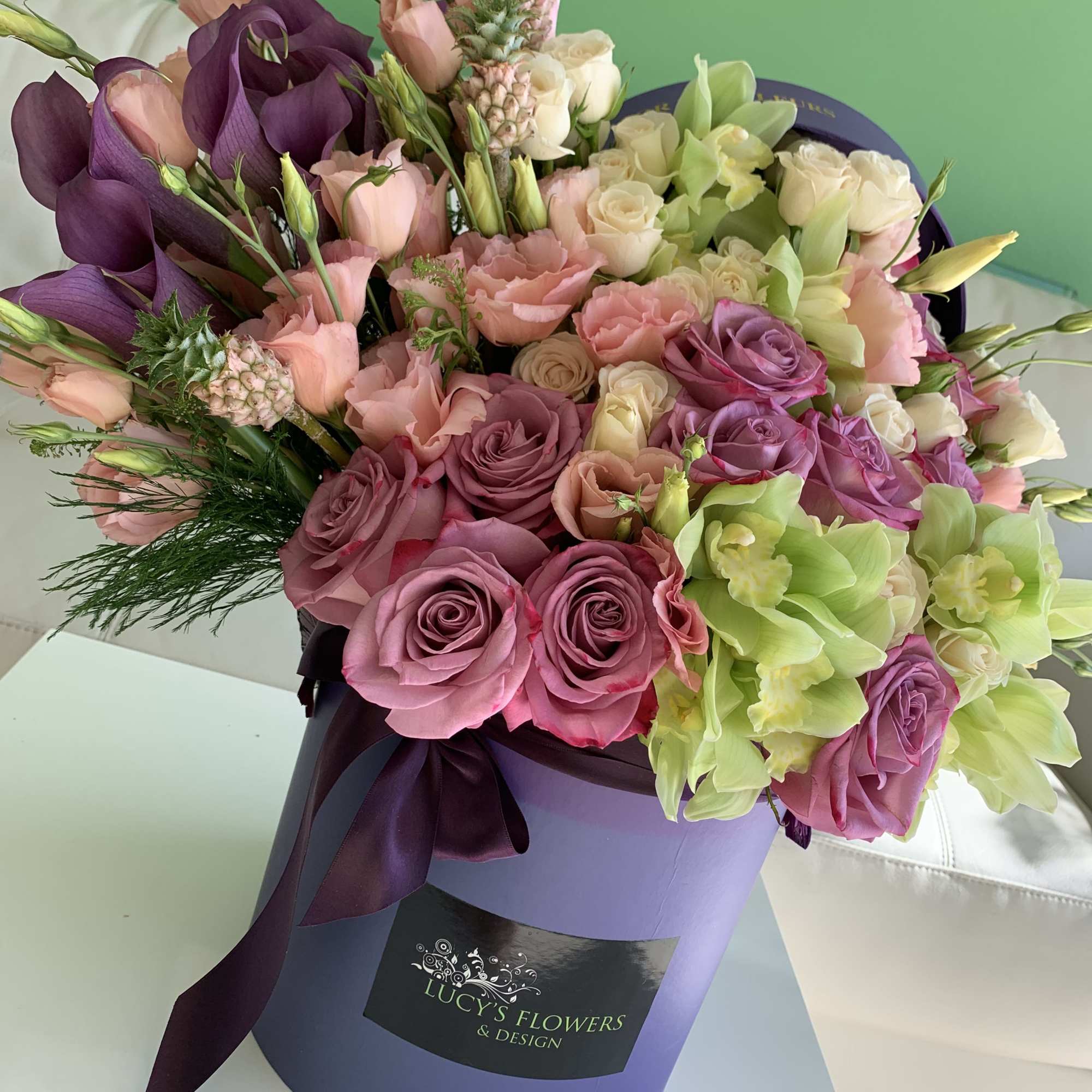 Mixed bouquet of pink, purple, white, and green flowers in a lavender hat box