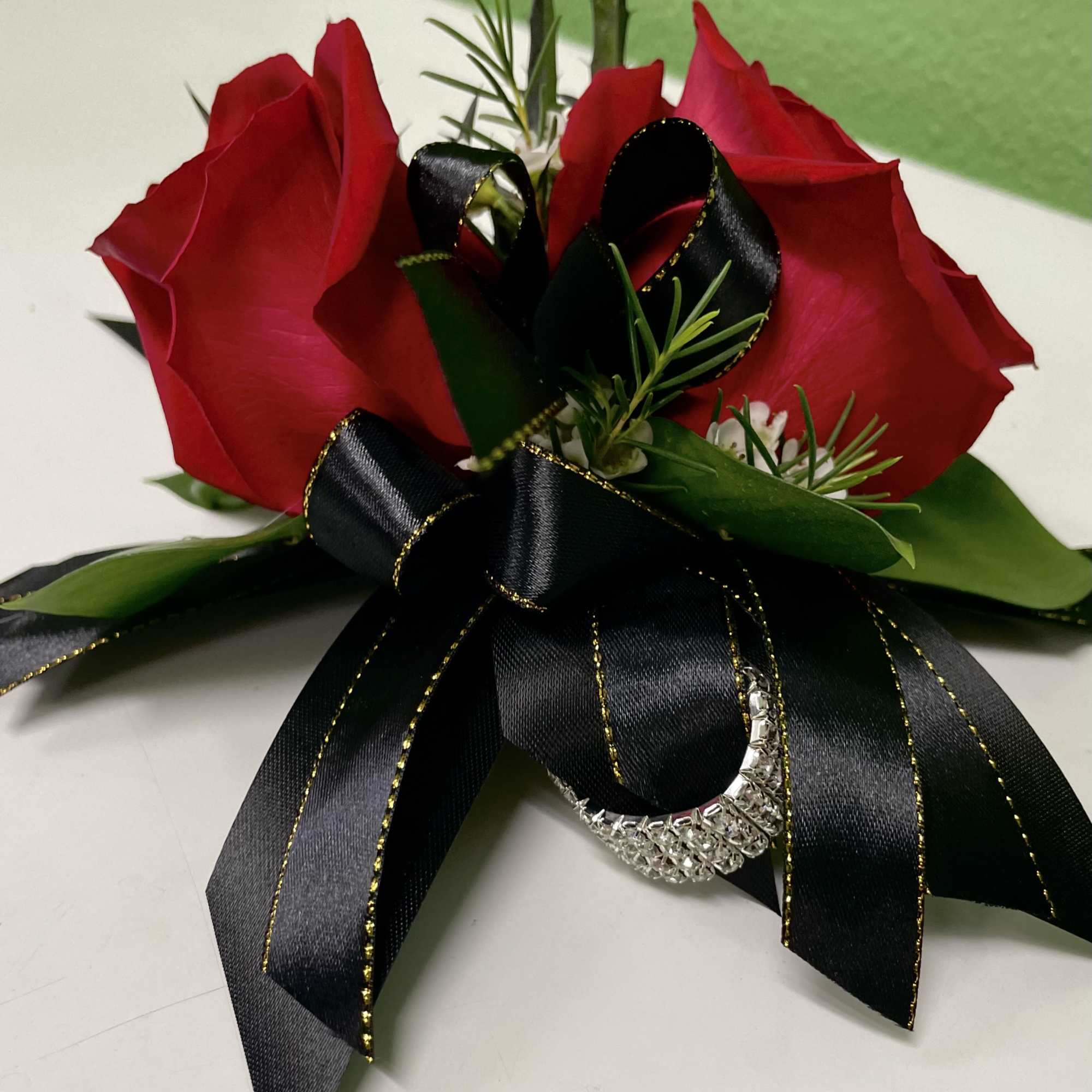 Two red roses with a black ribbon bow and silver accent