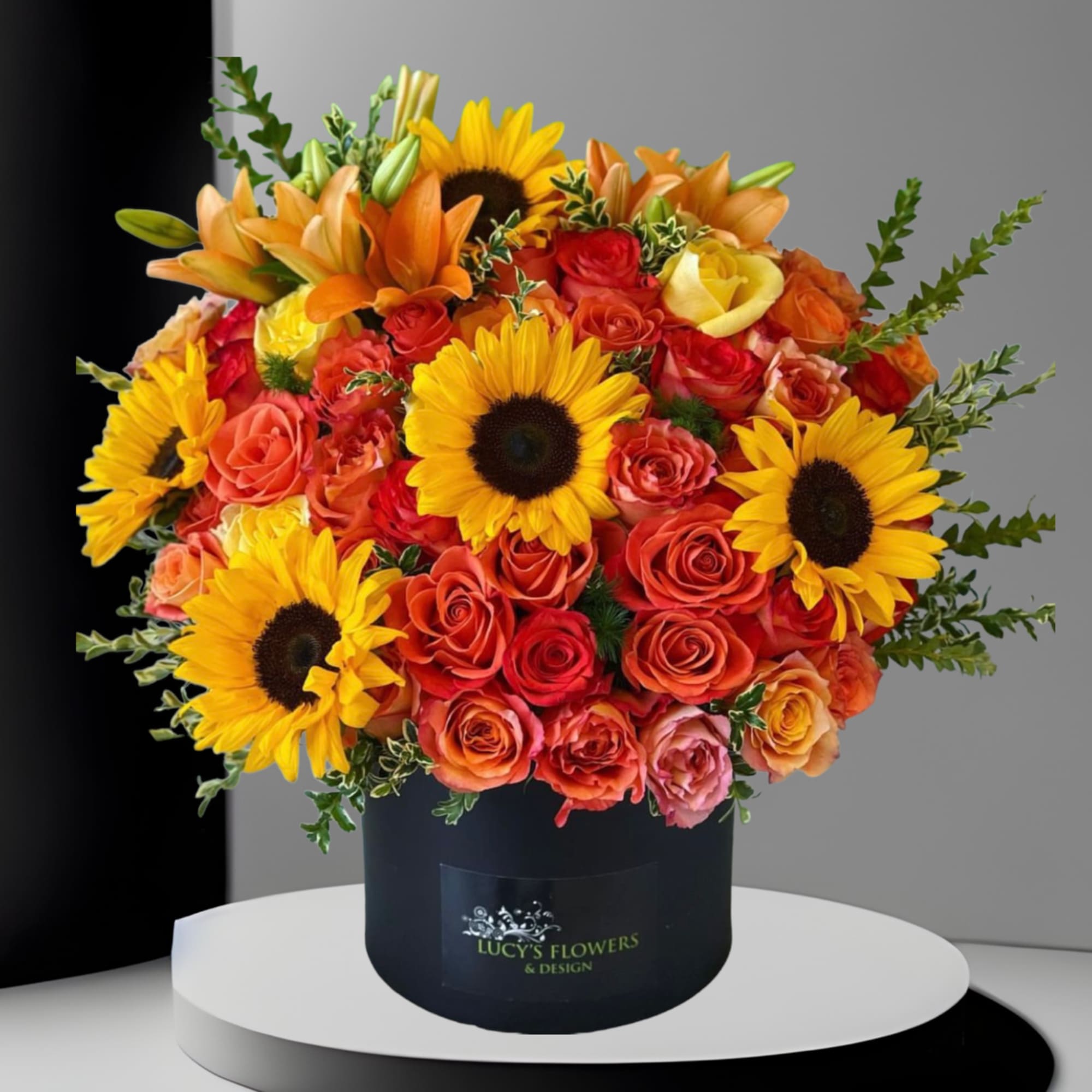 Bouquet of sunflowers and orange roses in a black hat box