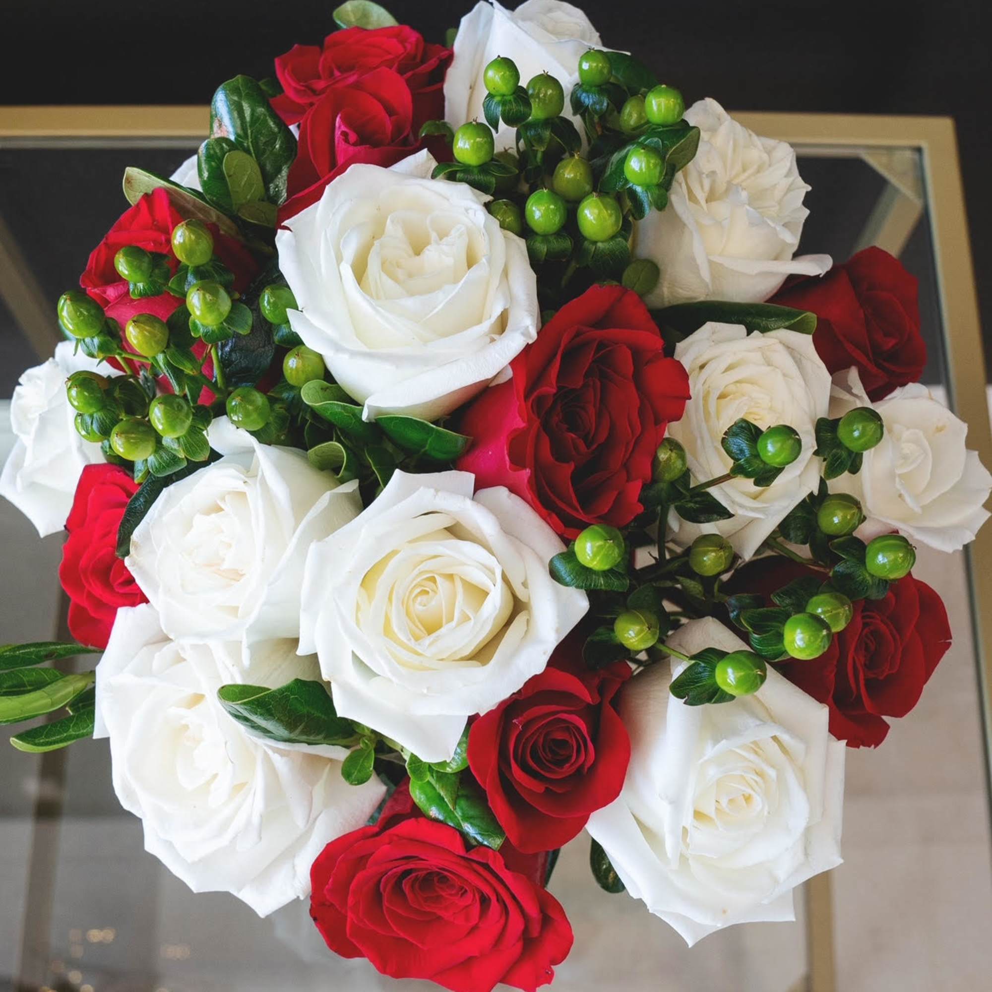 Bouquet of red and white roses with green berry accents