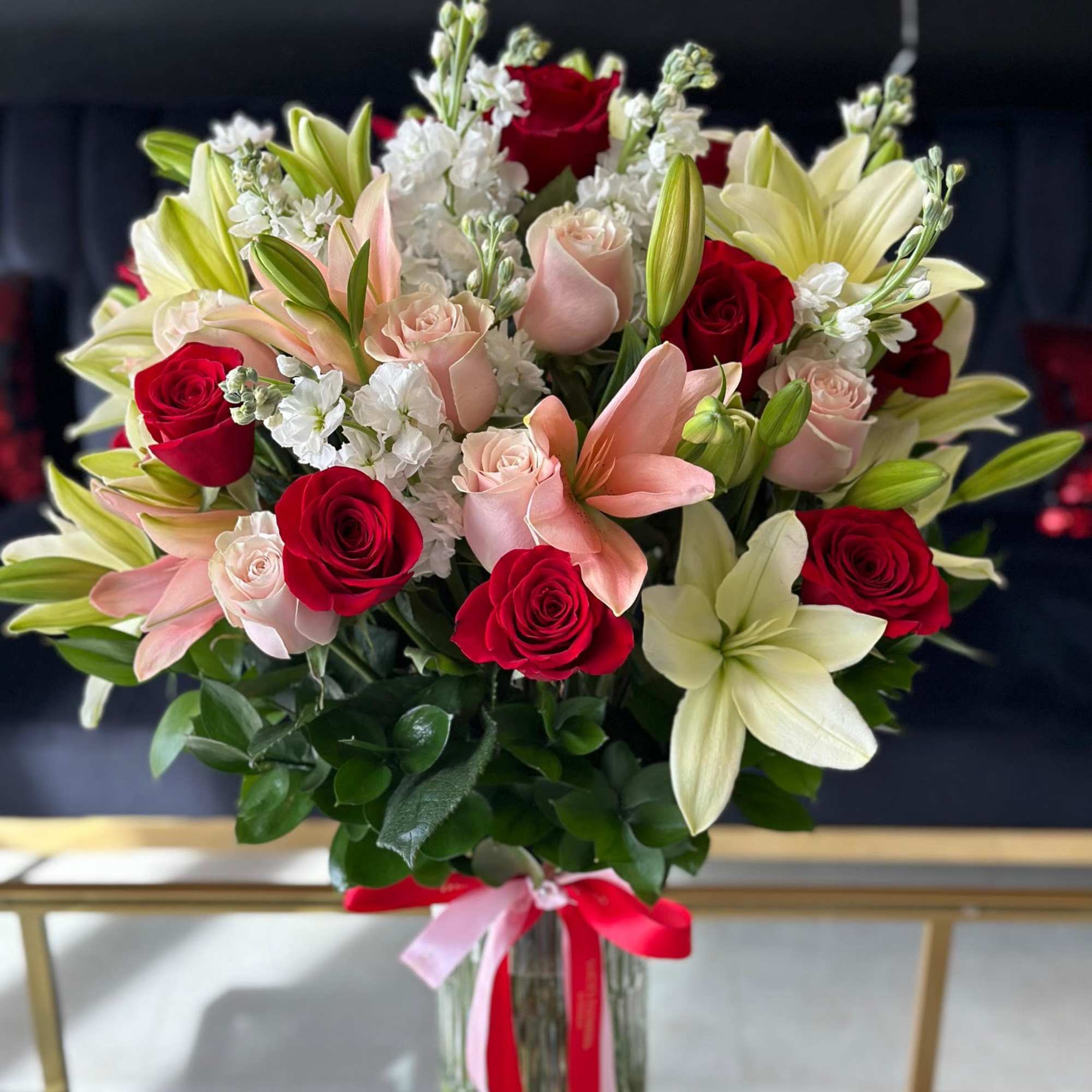 Bouquet of red and blush roses with lilies in a glass vase