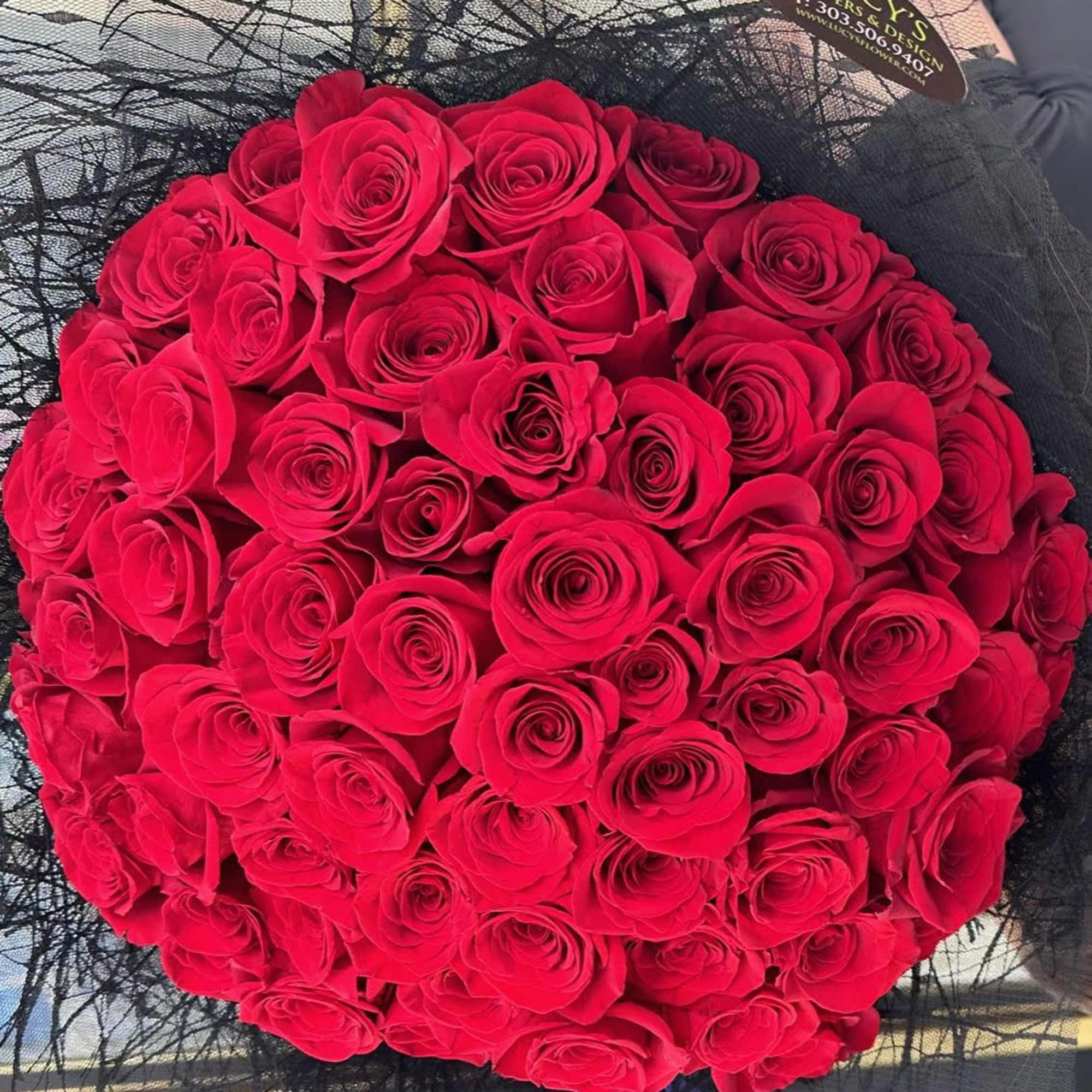 Round bouquet of red roses wrapped in black mesh