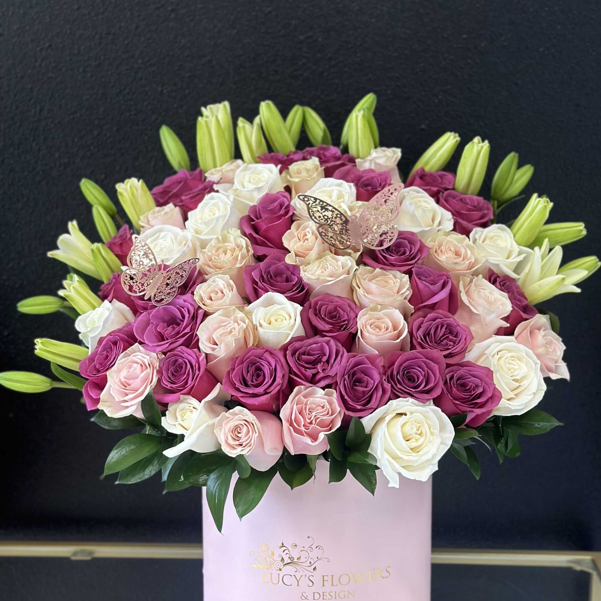 Pink, white, and peach roses in a round pink box with lily buds