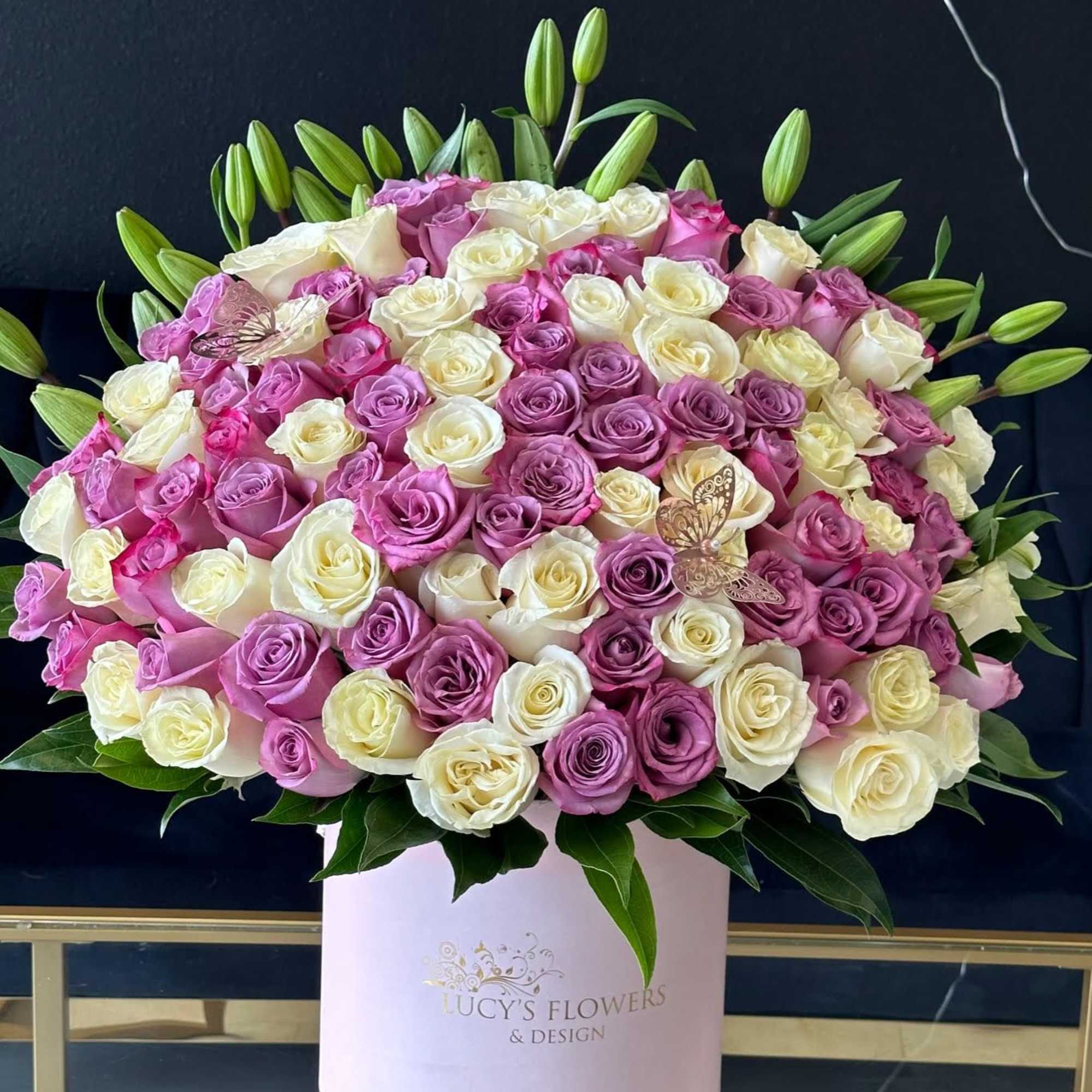 Large pink and white rose arrangement in a round box with lily buds