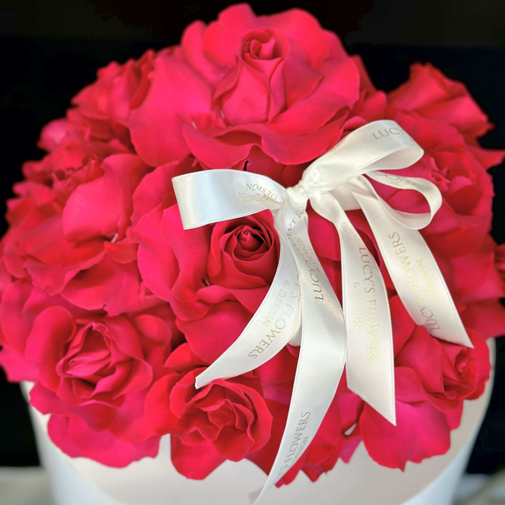 Hot pink rose bouquet with a white ribbon in a round box