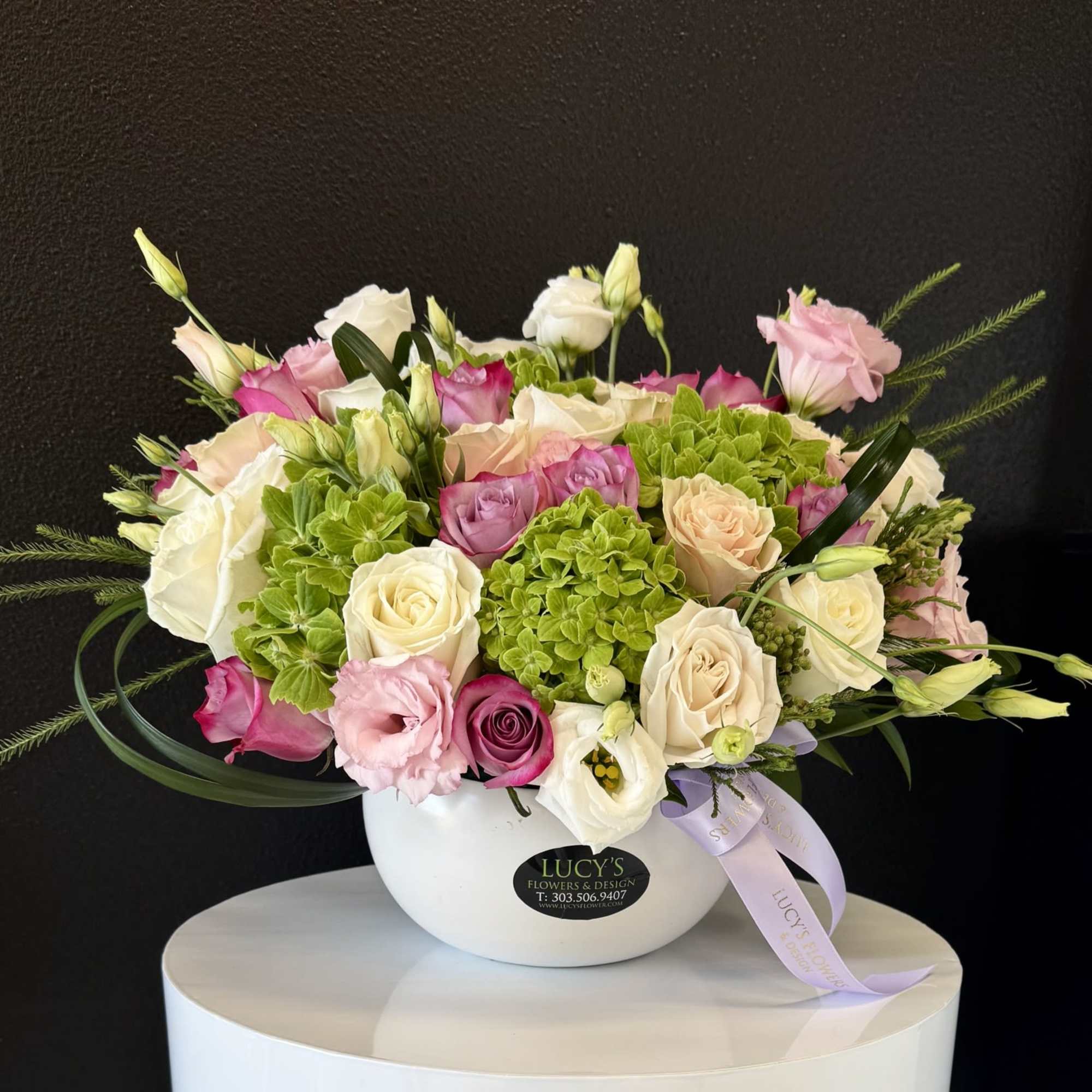 Mixed pink, white, and cream flowers arranged in a white bowl vase