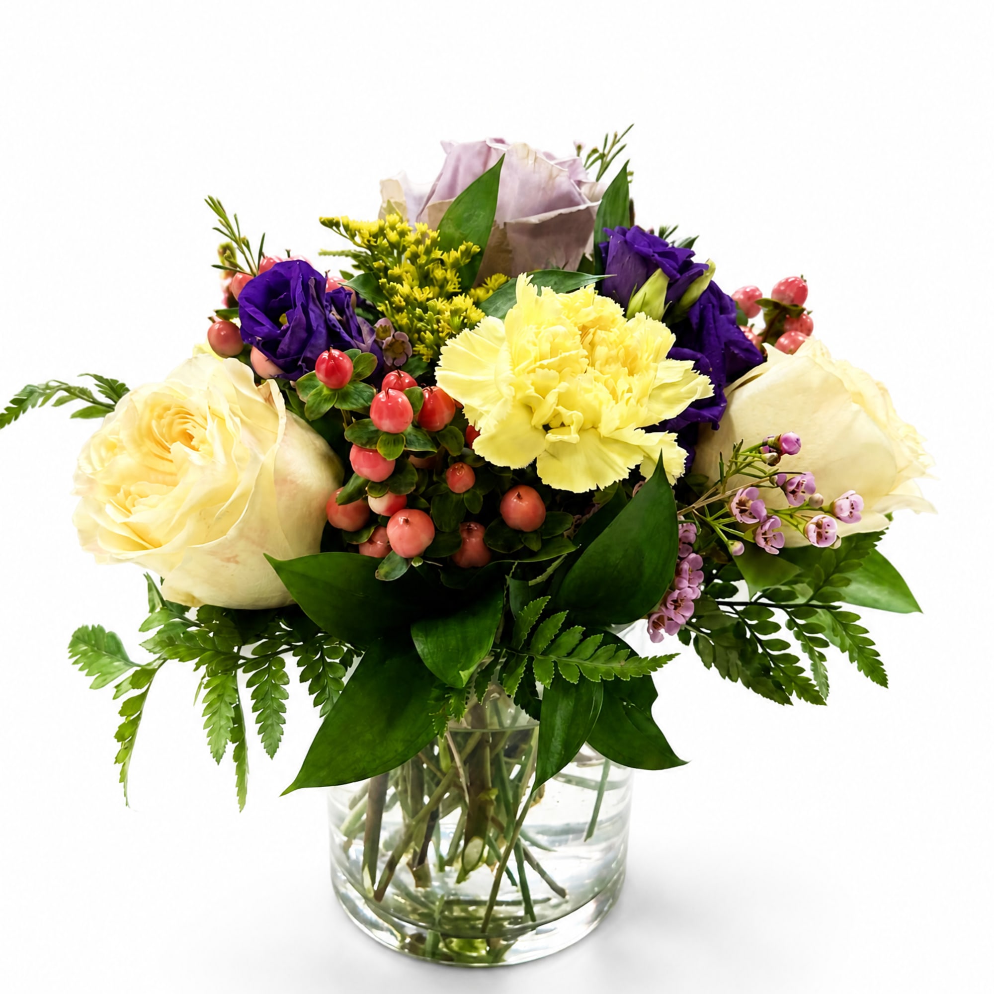 Mixed bouquet of cream, yellow, and purple flowers in a glass vase