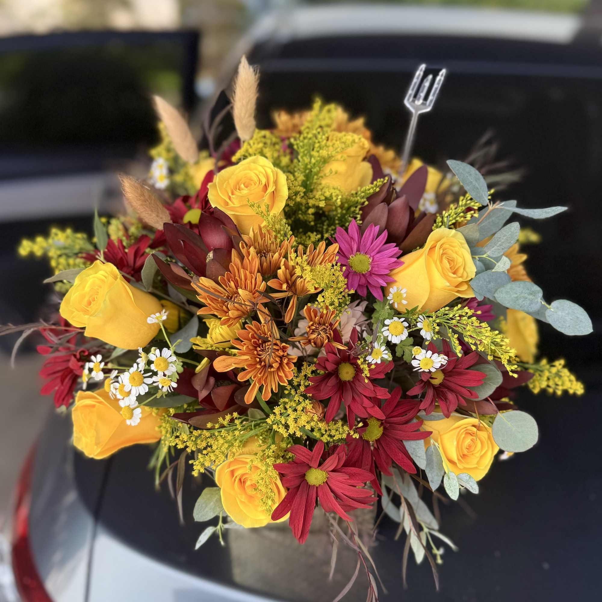 Mixed bouquet of yellow roses and red daisies with small filler flowers