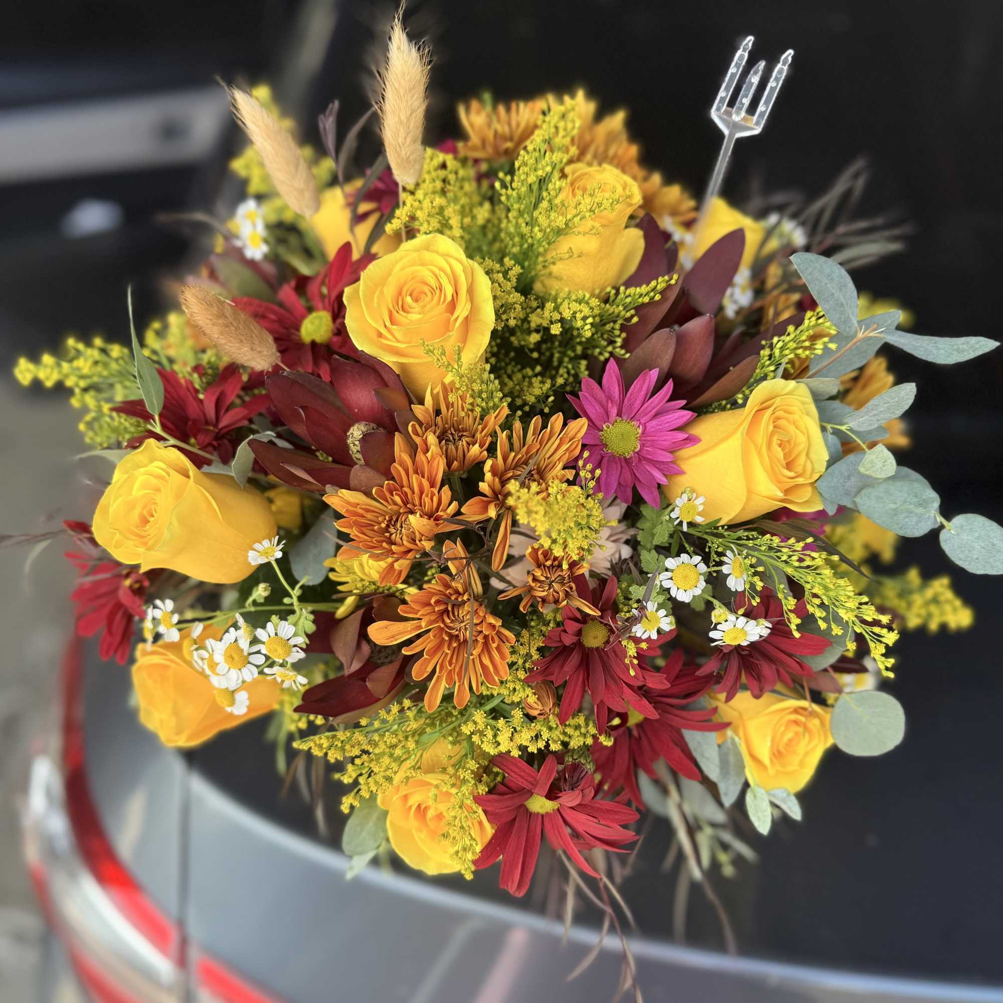 Bouquet of yellow roses, orange chrysanthemums, and burgundy daisies