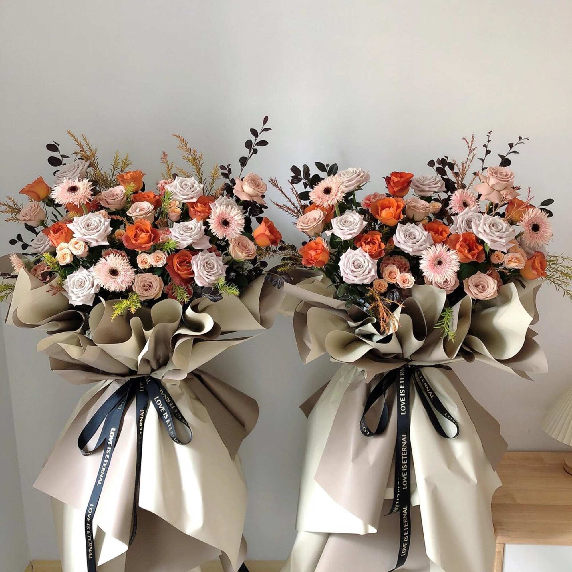 Two large bouquets of pink and orange roses with pale gerbera daisies