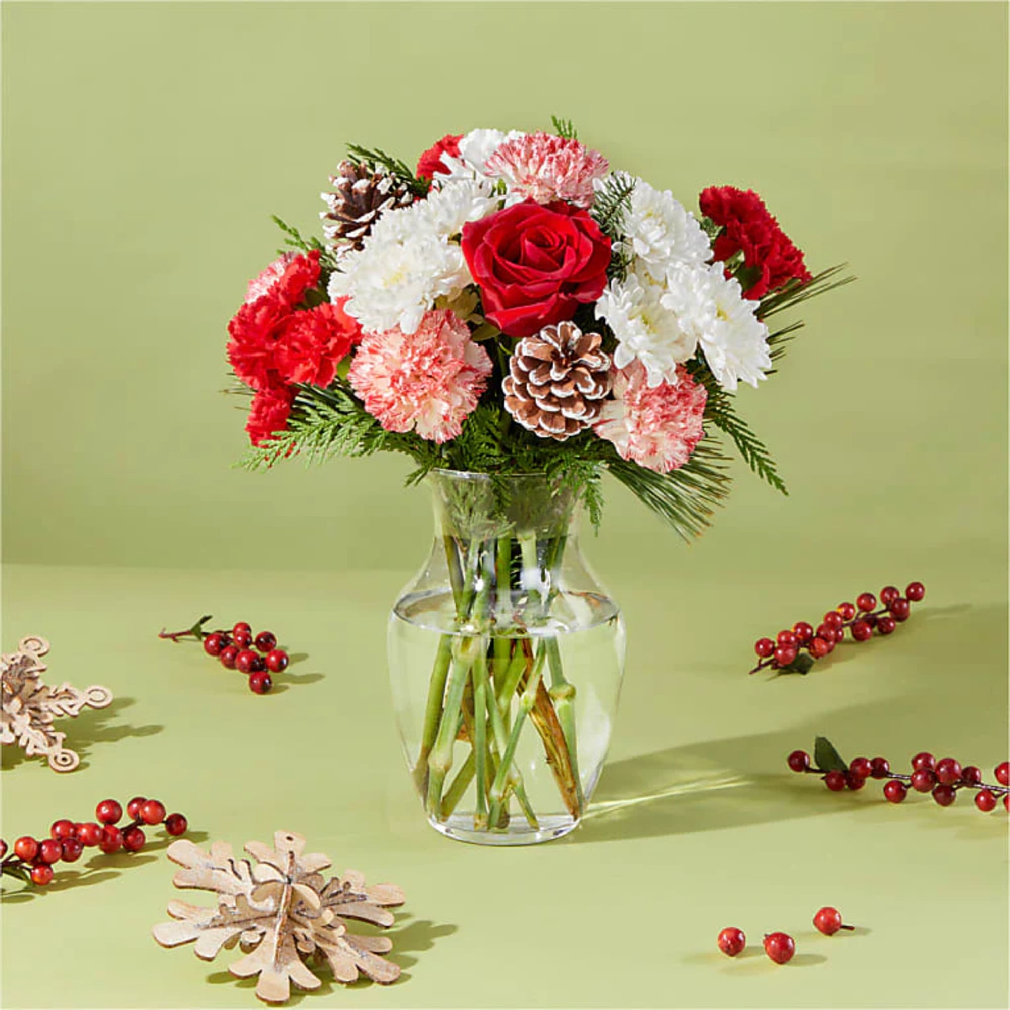 Bouquet of red and white carnations with pinecones in a clear glass vase
