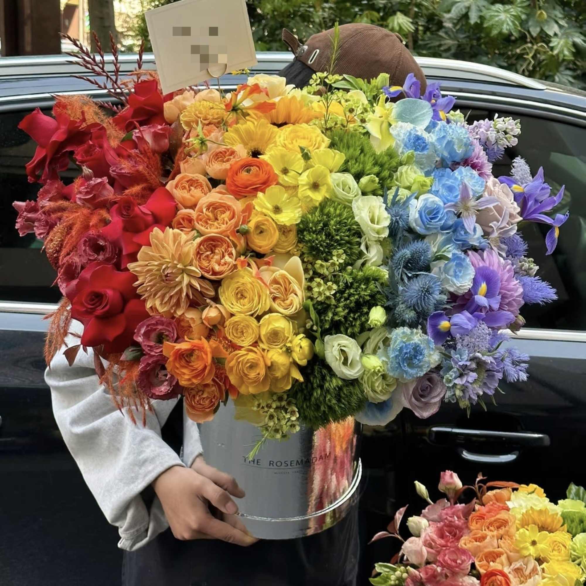 Large rainbow bouquet in a silver bucket held by a person