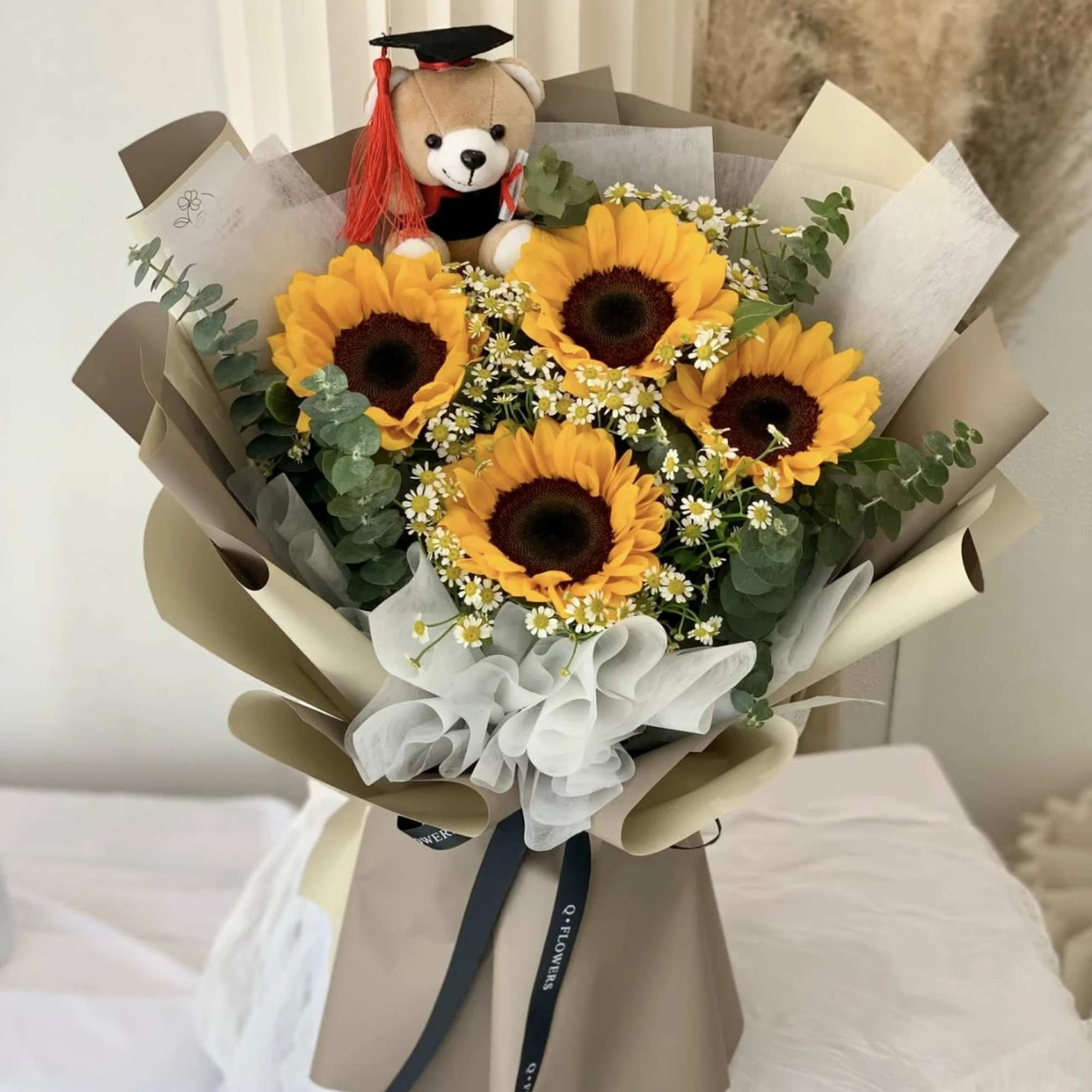 Bouquet of sunflowers with a teddy bear wearing a graduation cap