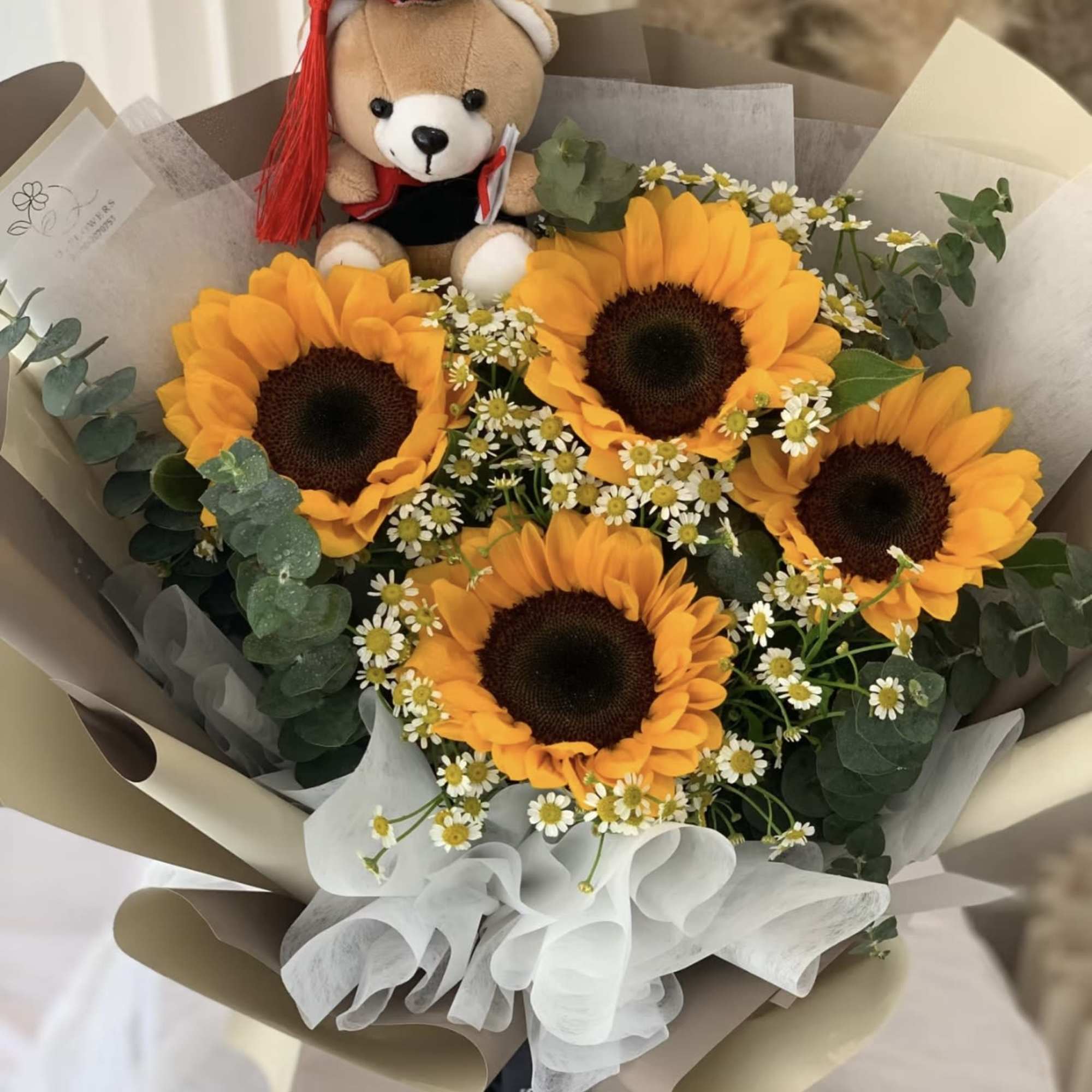 Bouquet of sunflowers with a teddy bear in a graduation cap