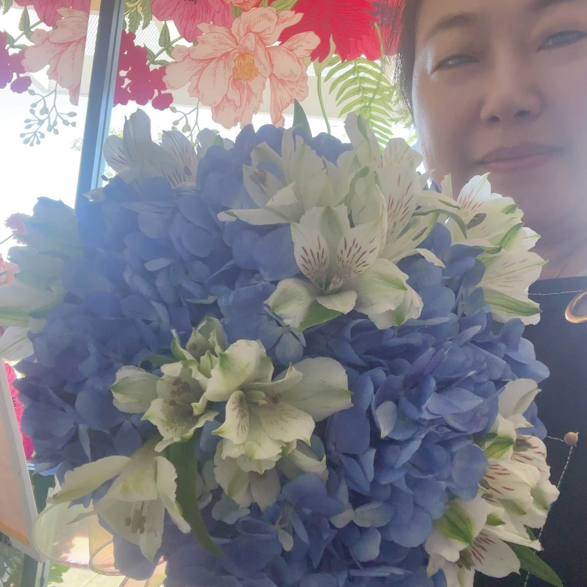 Woman holding a bouquet of blue hydrangeas and white alstroemeria