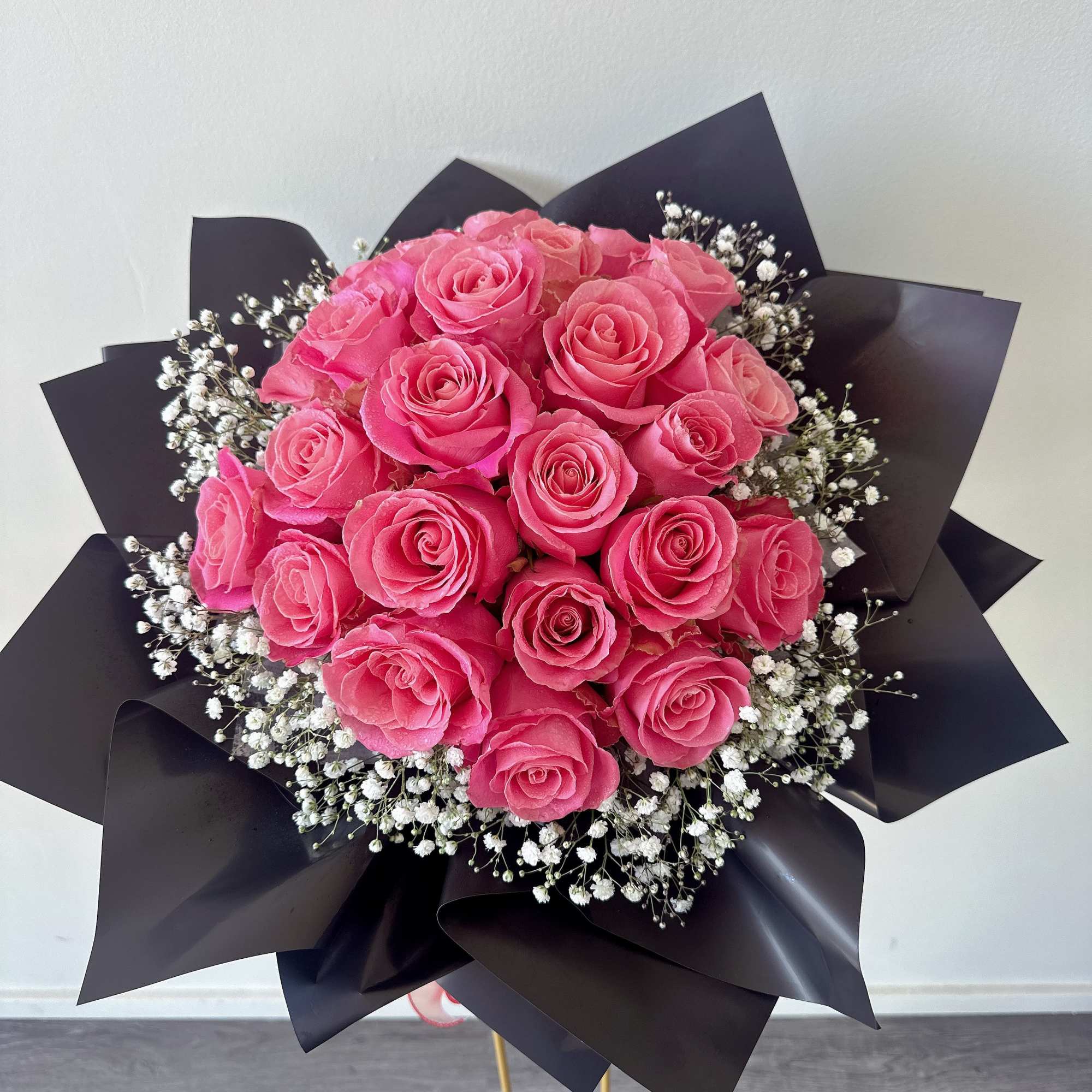 Bouquet of pink roses with white baby's breath in black wrap