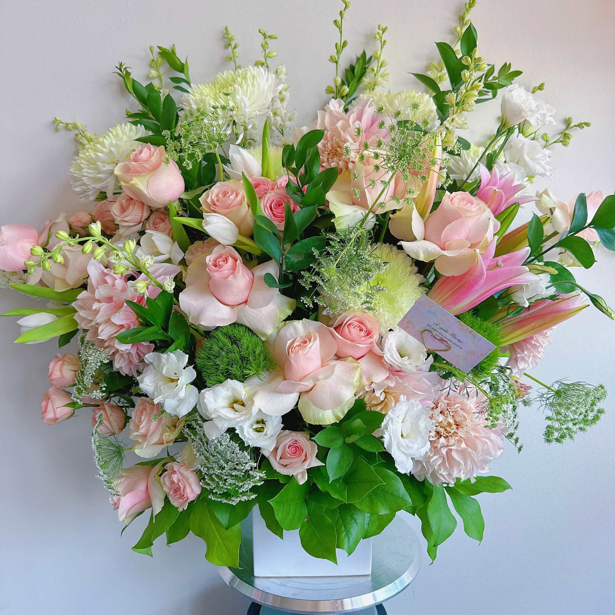 Large pastel bouquet with pink roses, white blooms, and green foliage in a white box