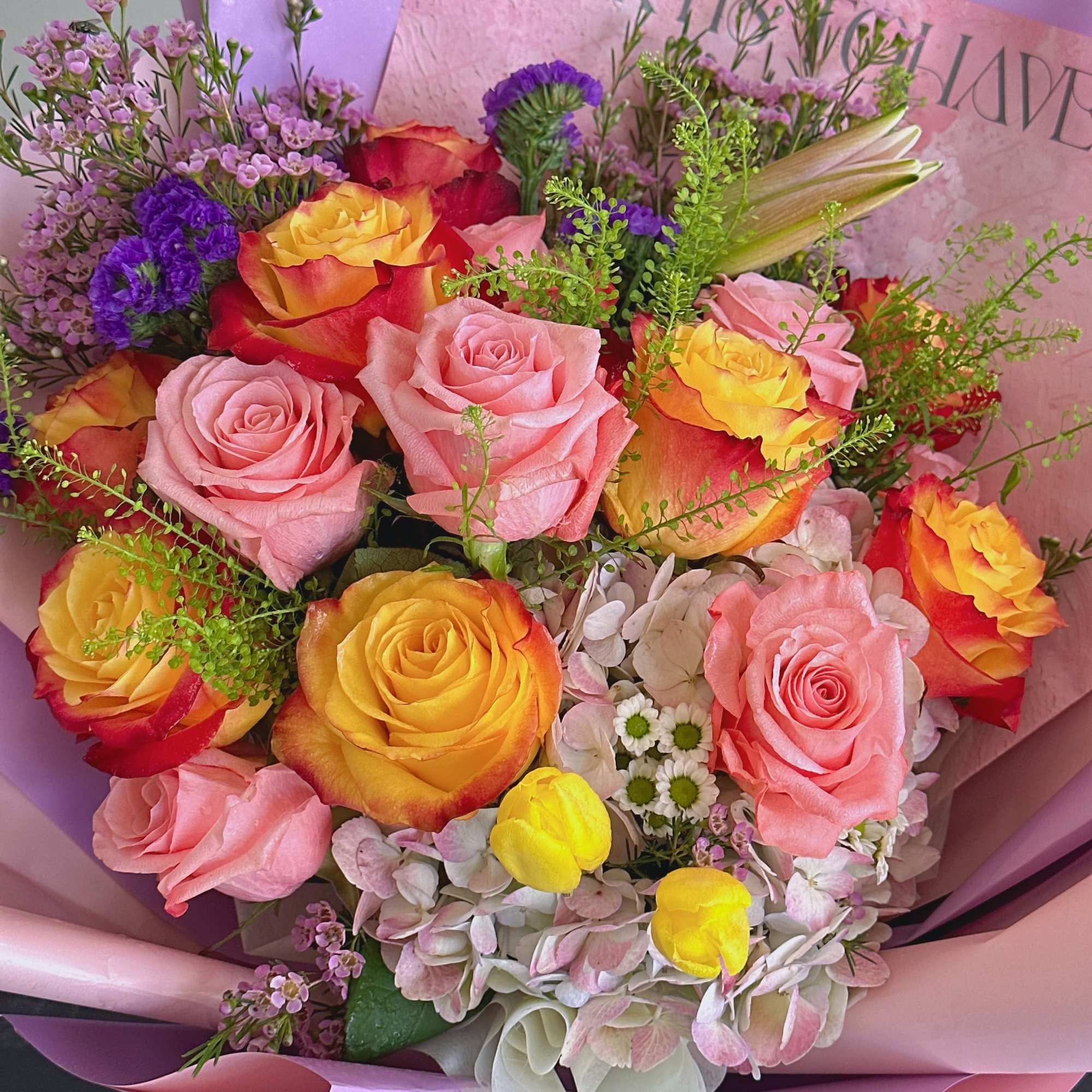 Bouquet of pink and yellow roses with purple filler flowers