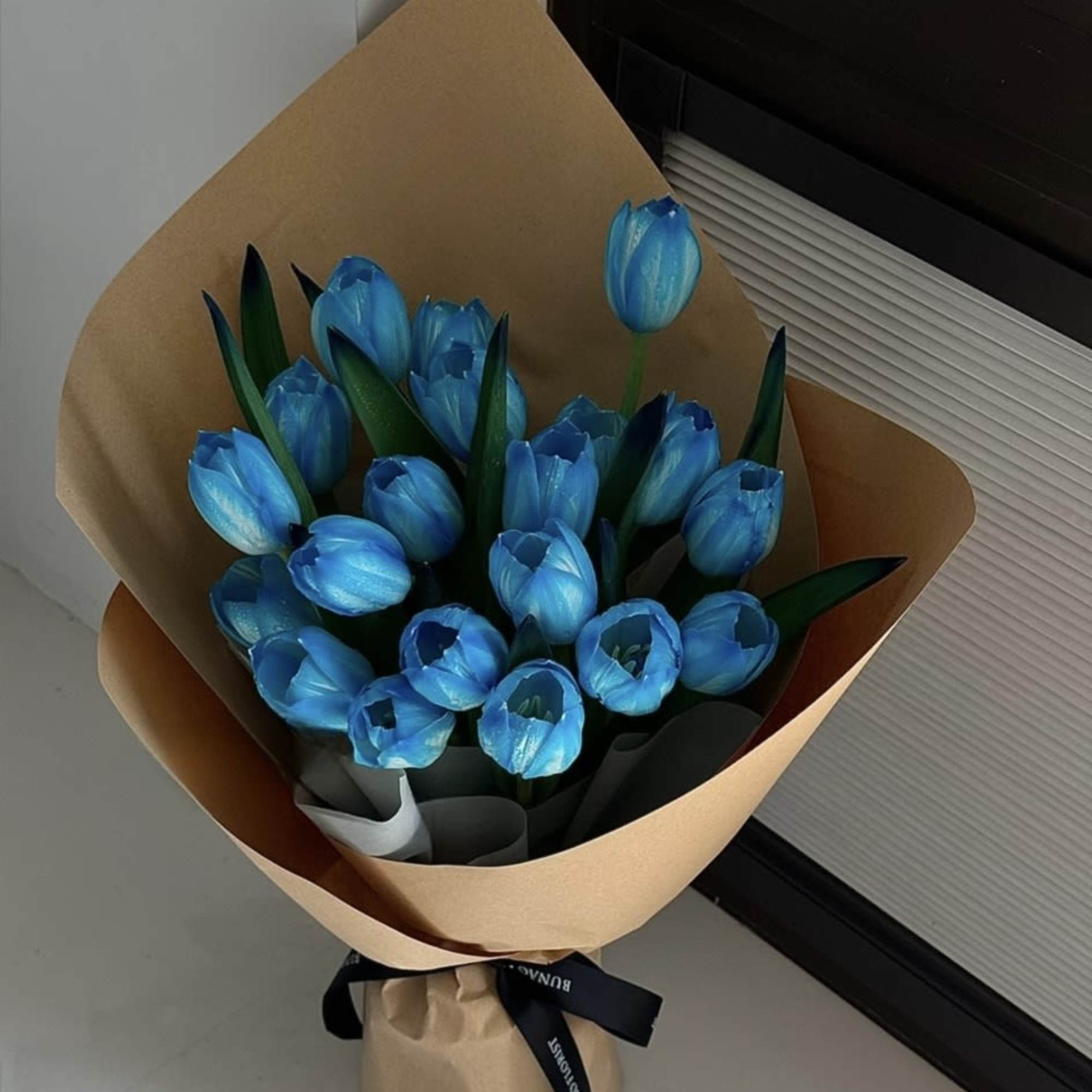Bouquet of bright blue tulips wrapped in brown paper, photo 2 of 3