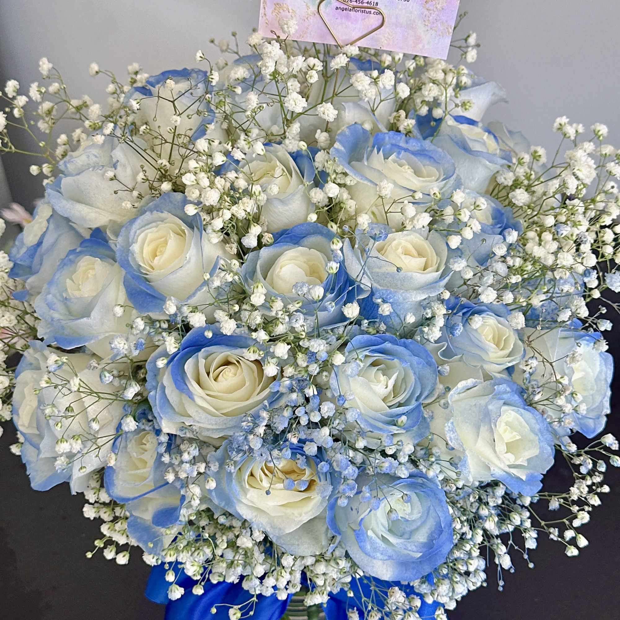 Blue-tinted white rose bouquet with baby's breath in a glass vase