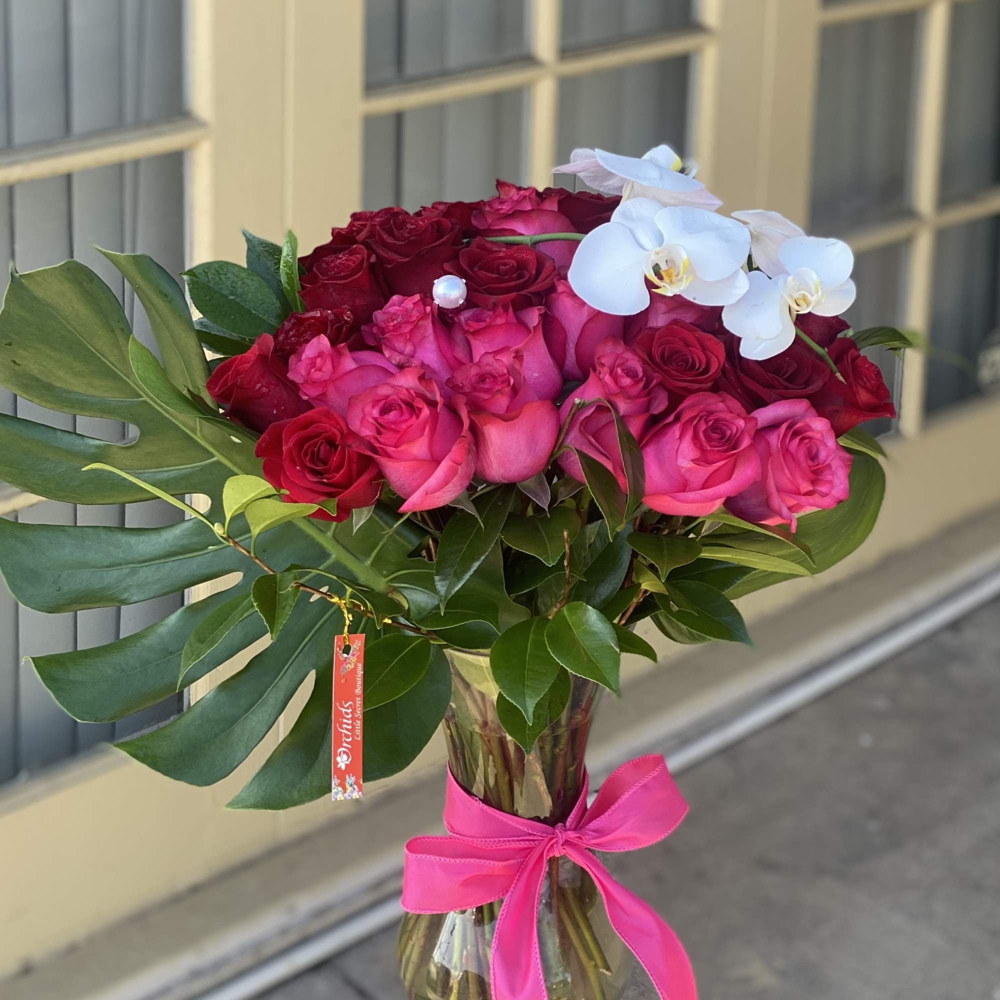 Bouquet of pink and red roses with white orchids in a glass vase