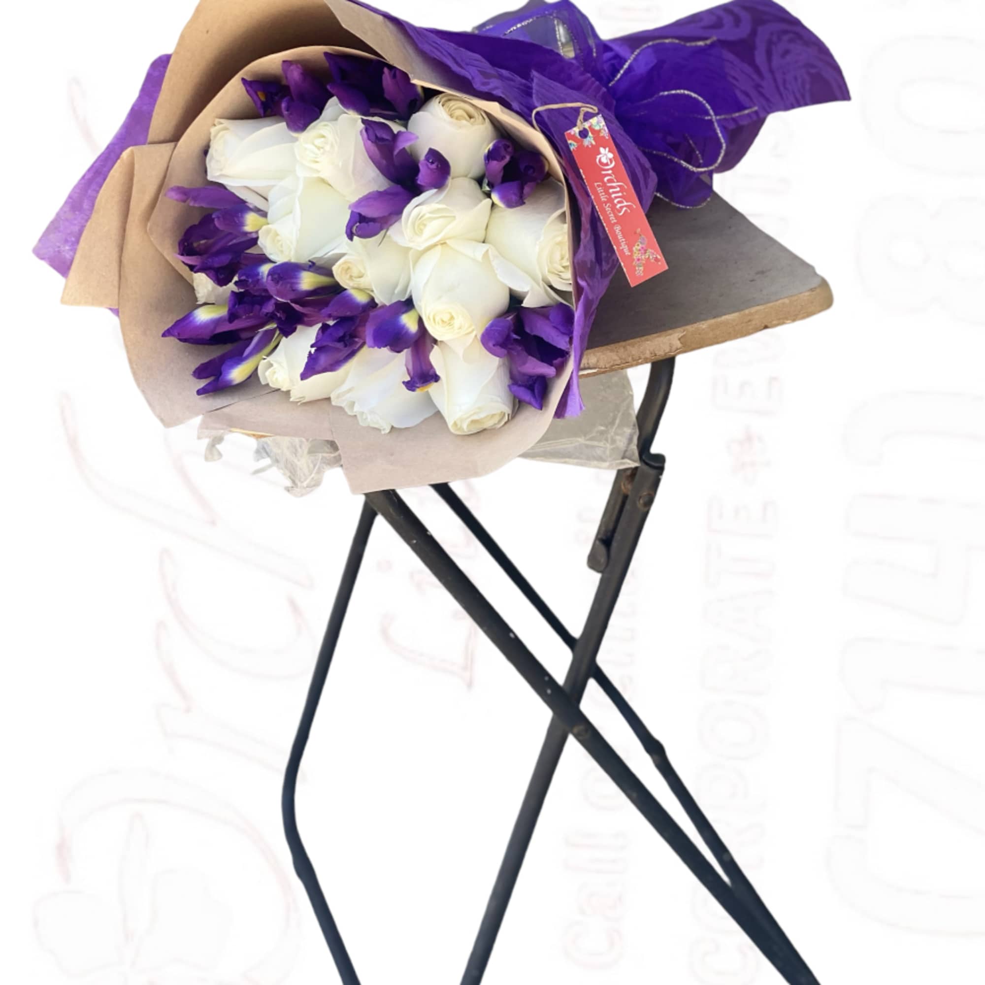 Bouquet of white roses and purple irises wrapped in tan and purple paper