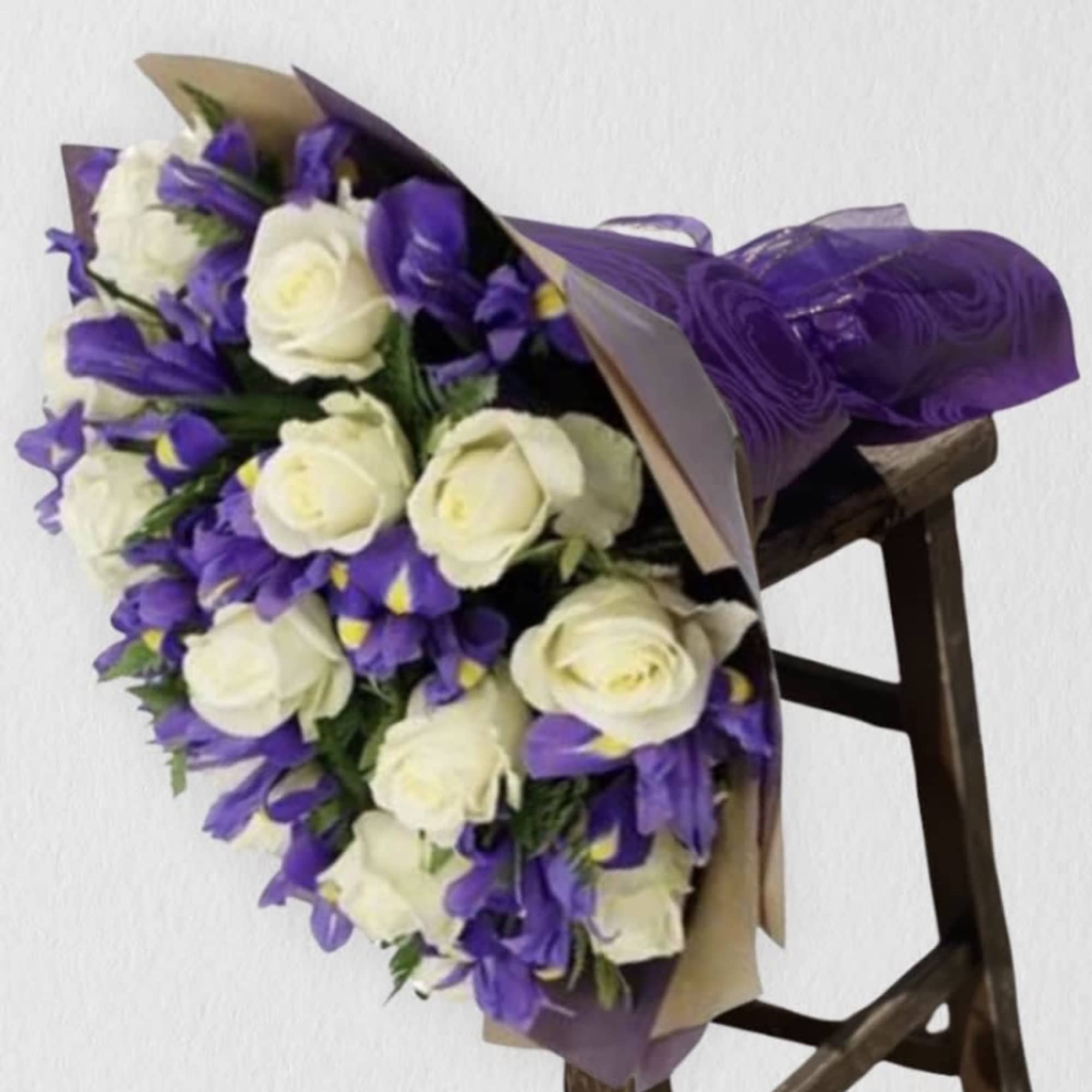 Bouquet of white roses and purple flowers wrapped in purple paper