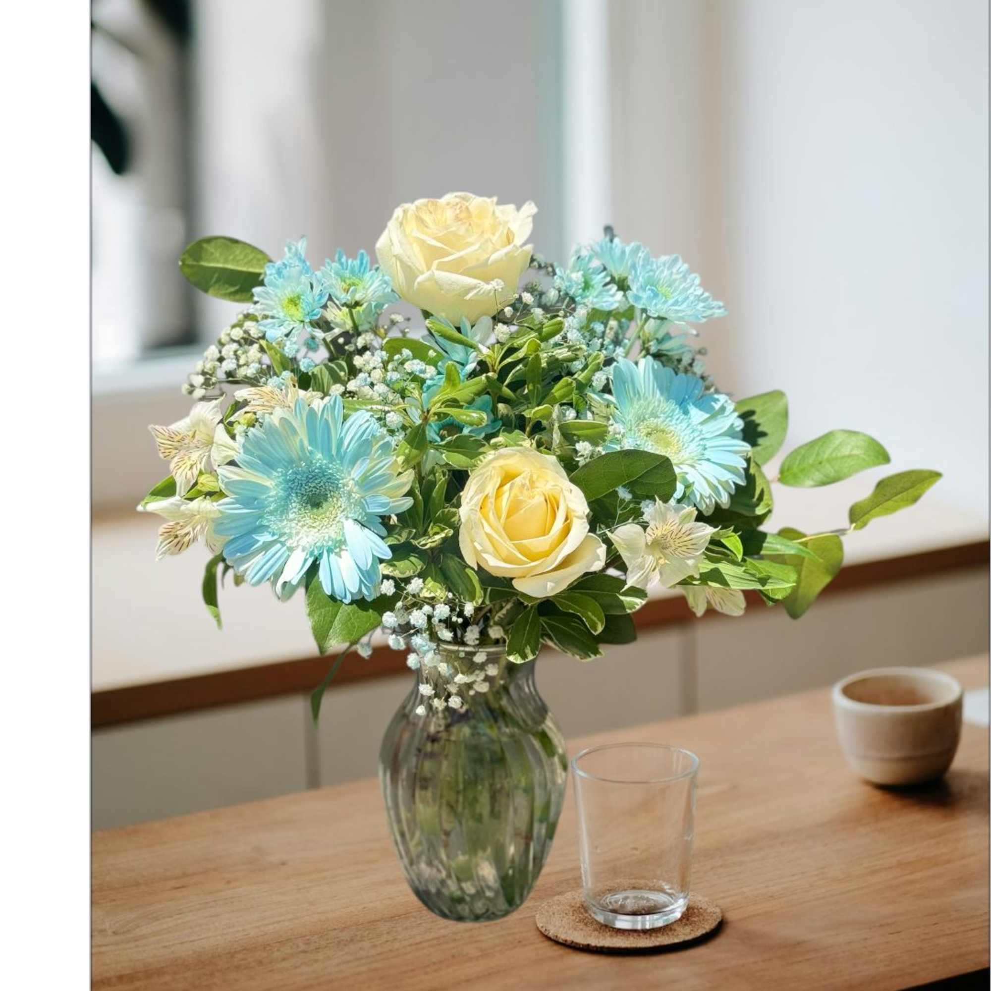 Blue and cream flowers arranged in a glass vase on a table