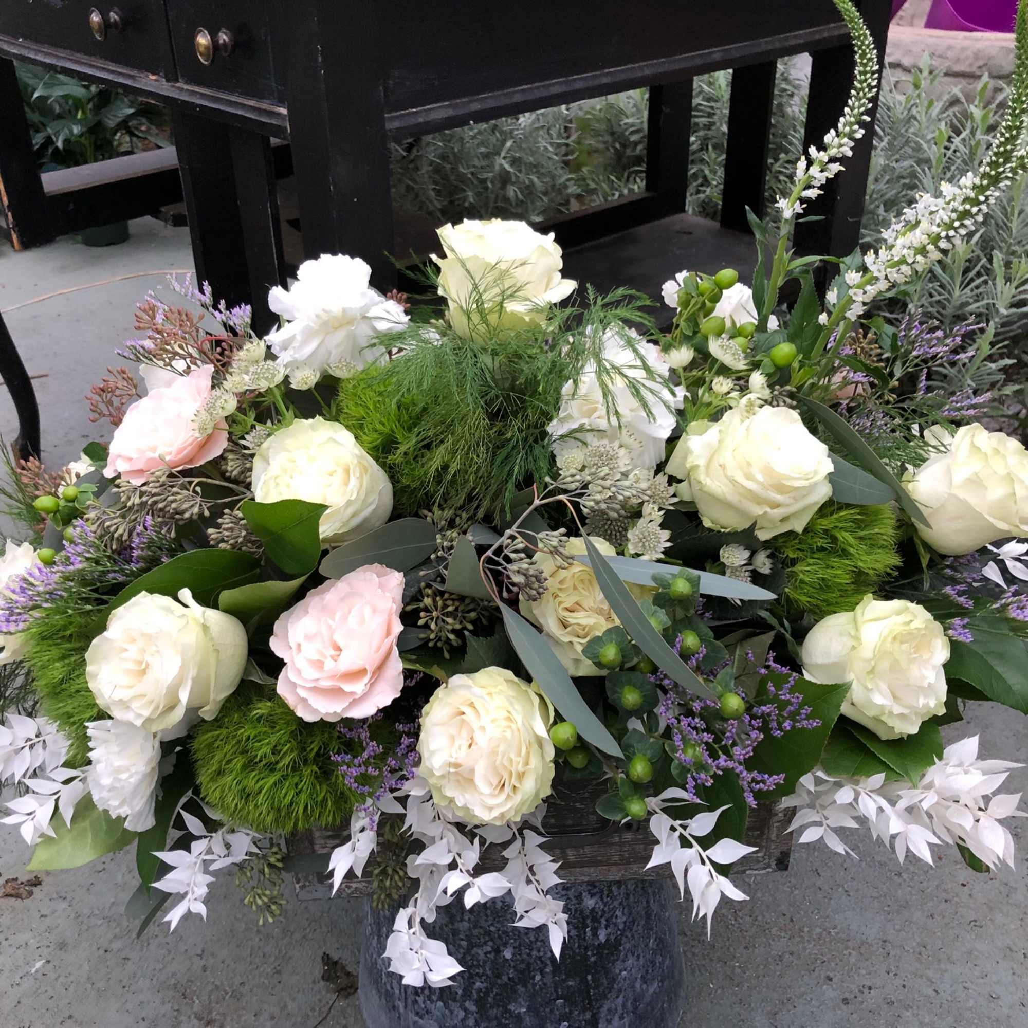 Large floral arrangement with white and pale pink roses in a container