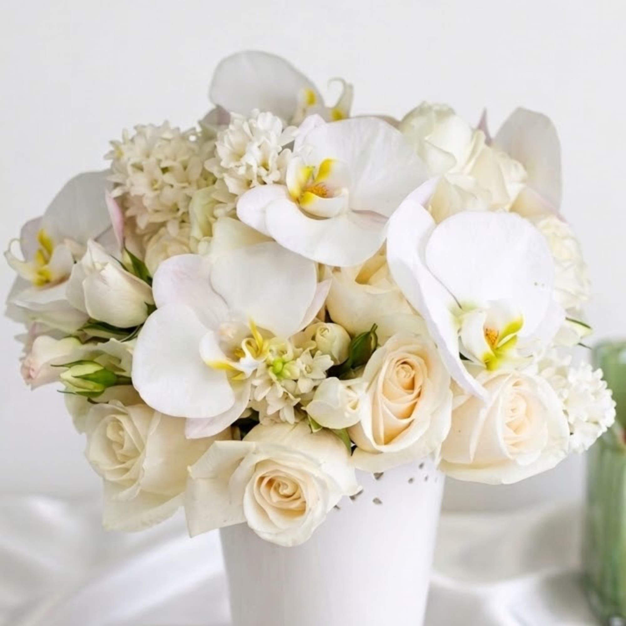 White orchids and cream roses arranged in a white vase