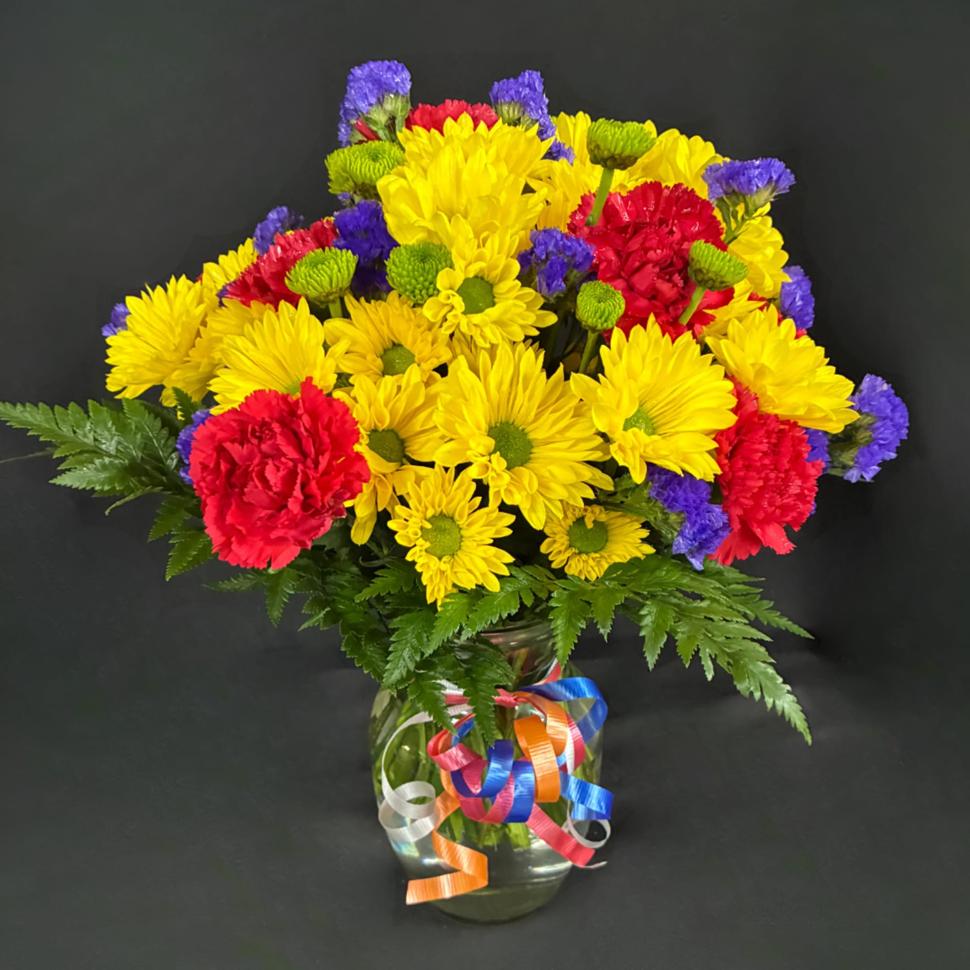 Colorful bouquet of yellow, red, and purple flowers in a glass vase
