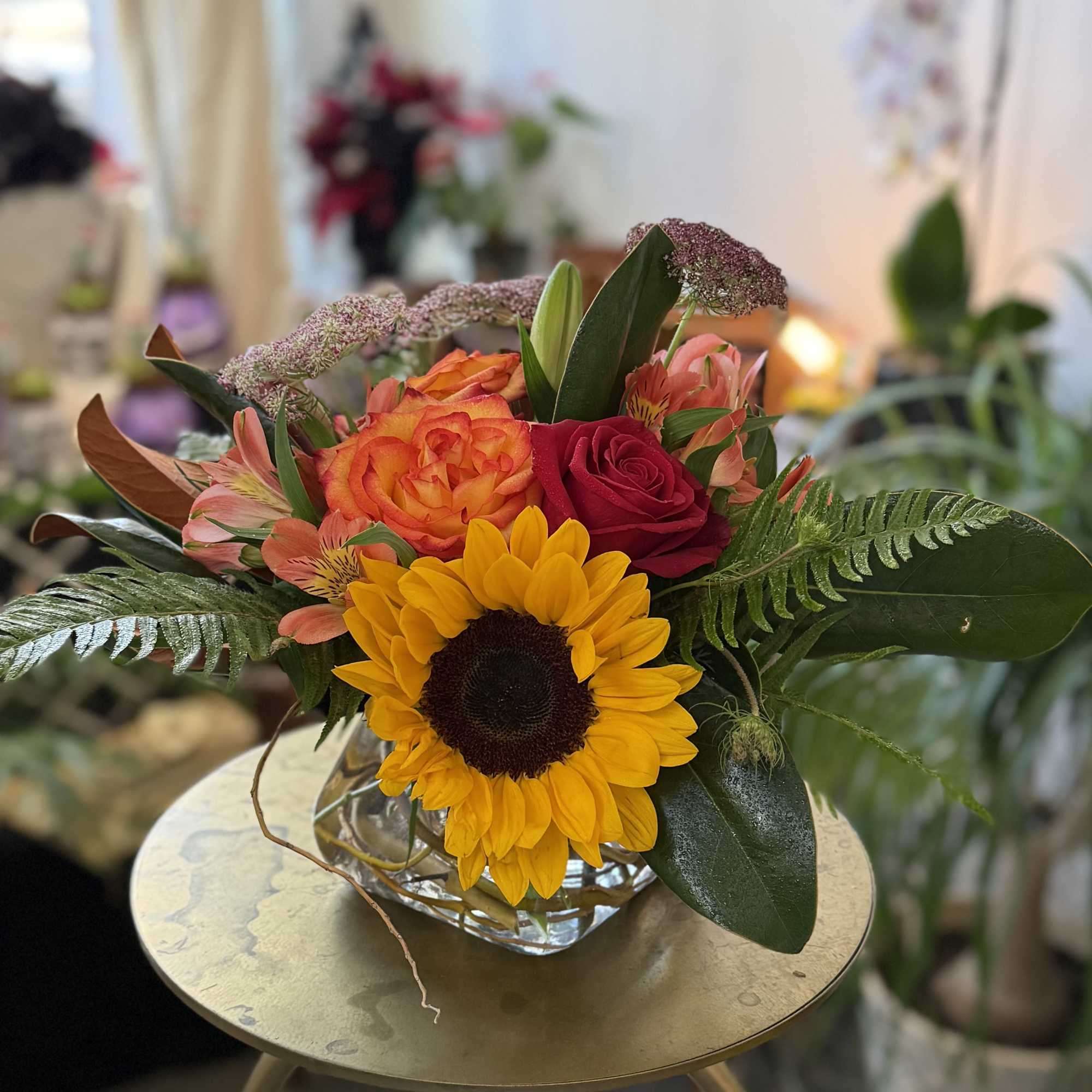 Mixed bouquet with a sunflower, roses, and pink alstroemeria in a glass vase