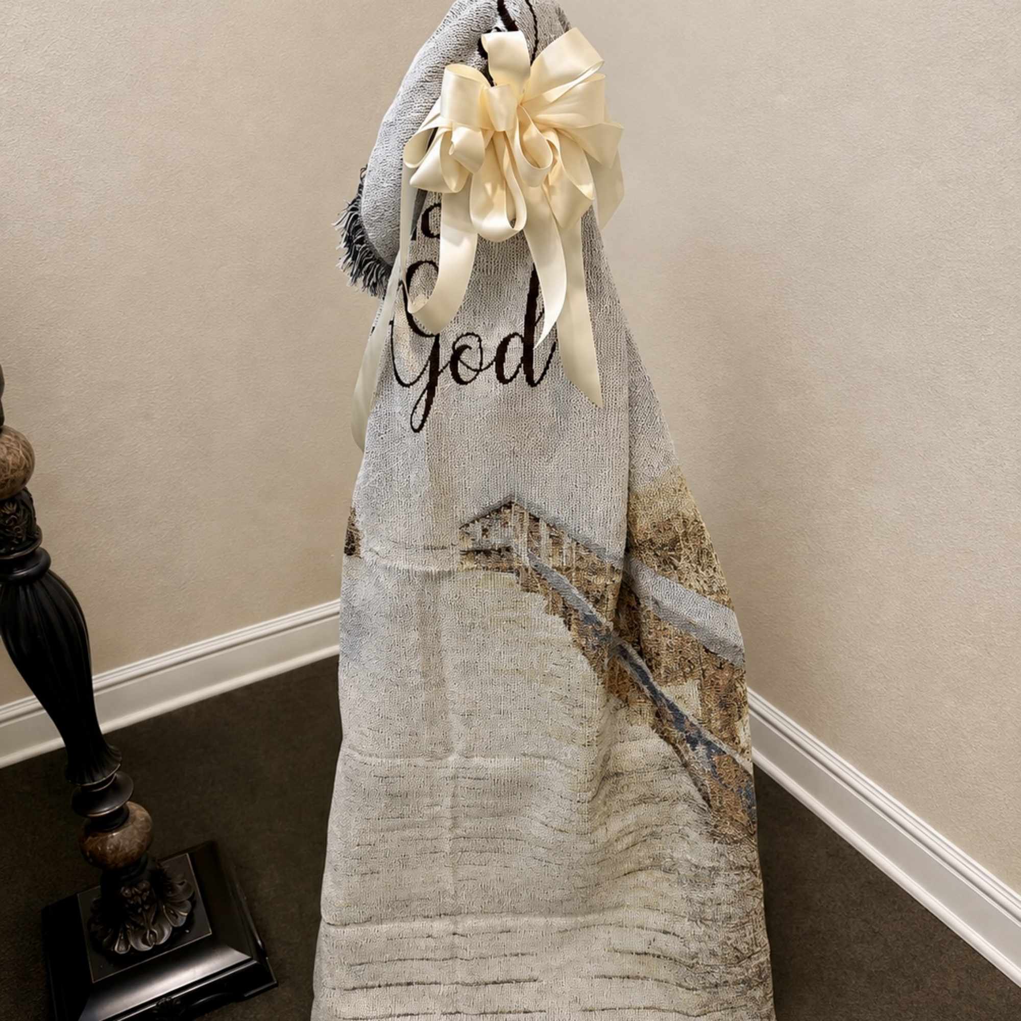 Decorative blanket draped over a stand with a cream ribbon bow