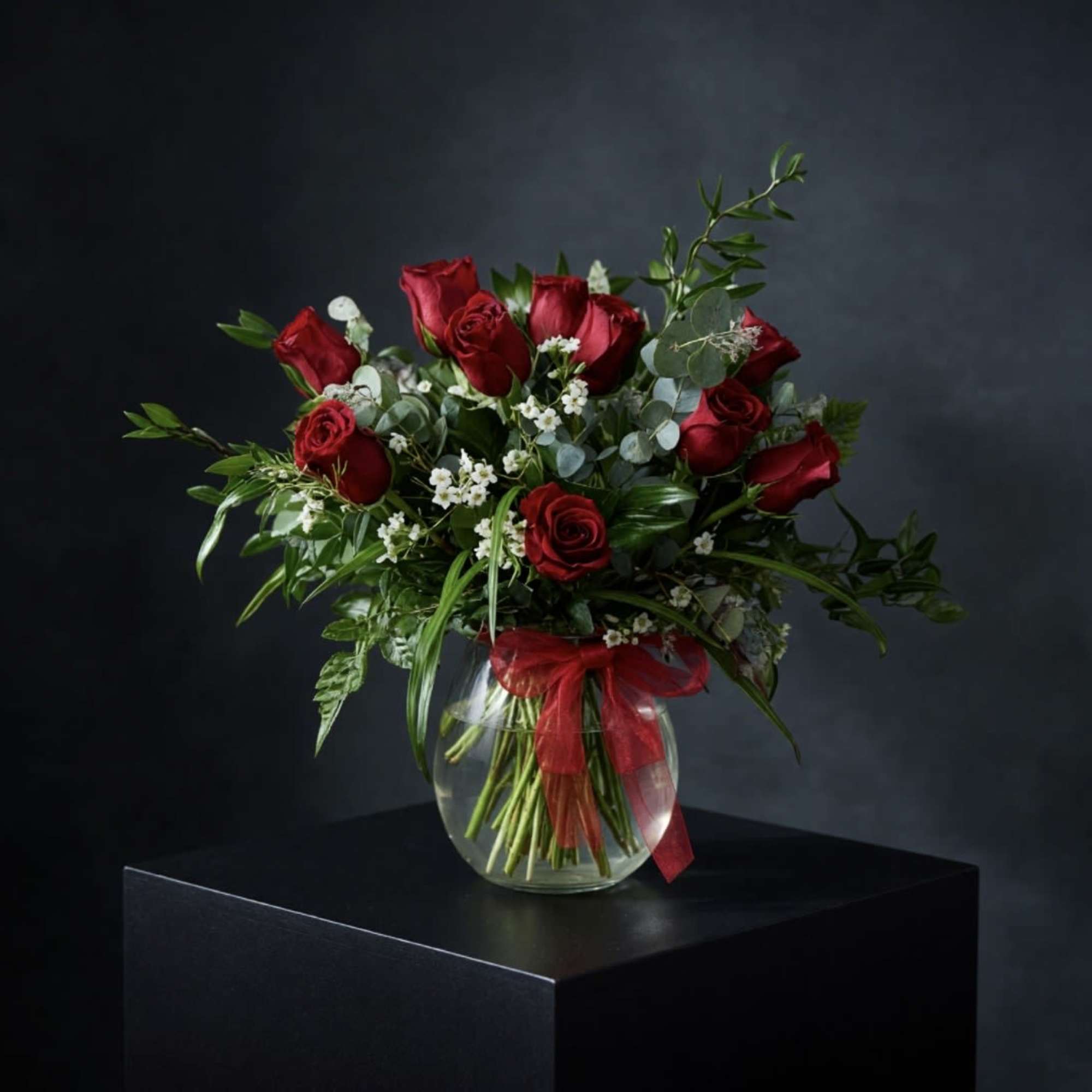 12 Red roses accented with premium greens in a  clear vase.