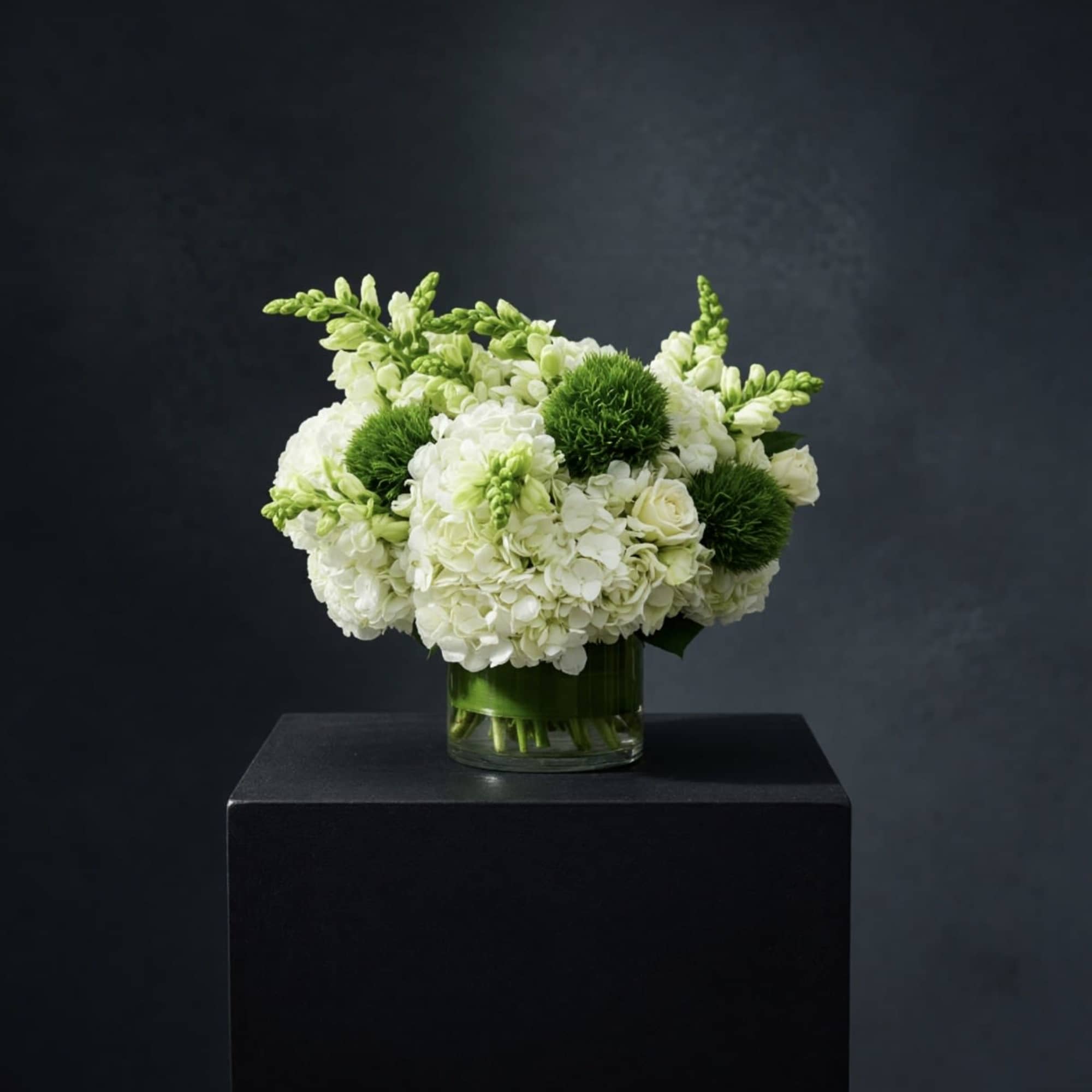 White and green floral arrangement in a glass vase