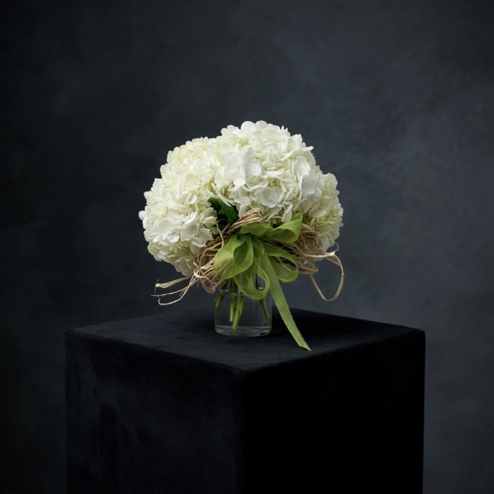 Hand gathered hydrangeas clustered together and placed in a cylinder vase accented