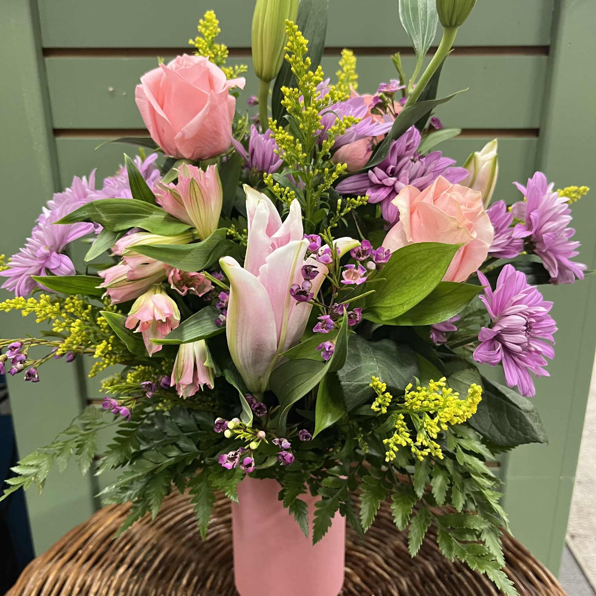 Pink roses and lilies in a pink vase with purple flowers