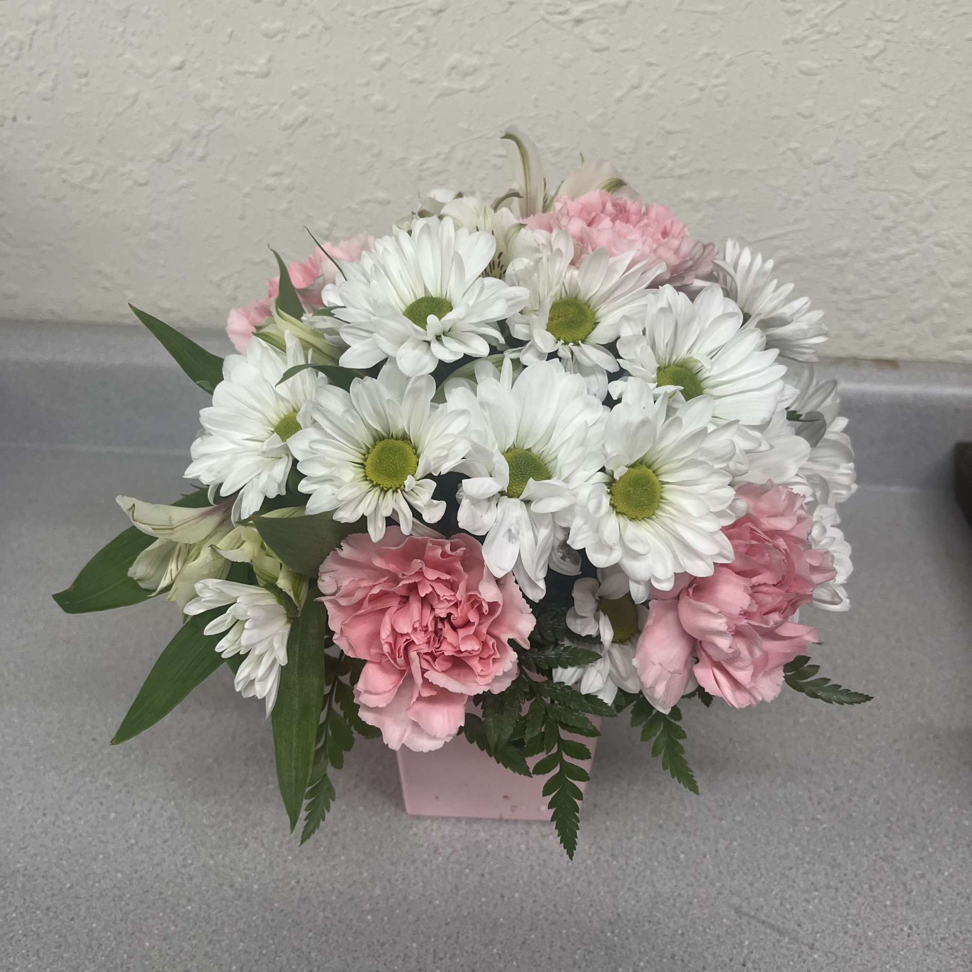 Pink carnations and white daisies in a pink box
