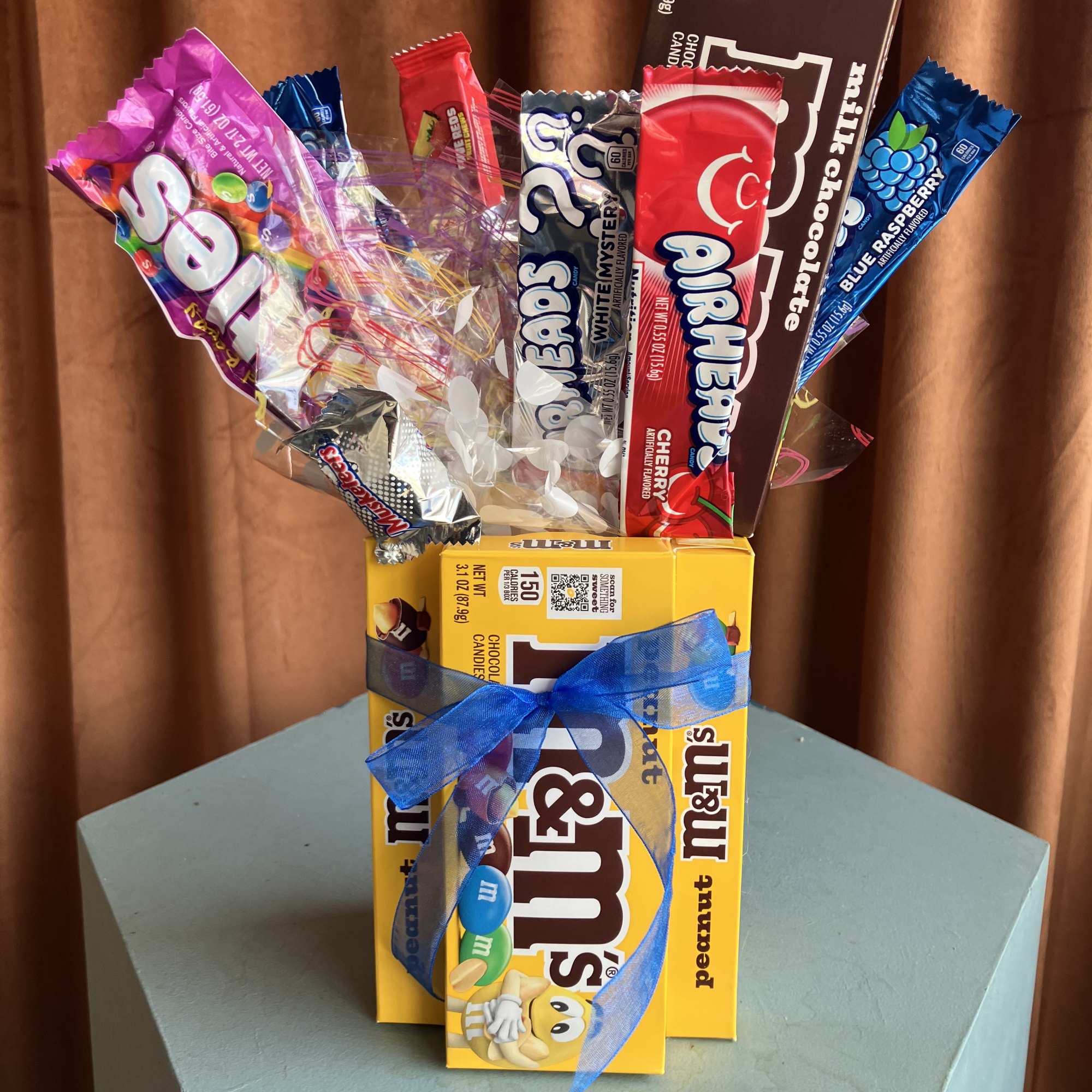 Assorted candy bars arranged like a bouquet with a blue ribbon
