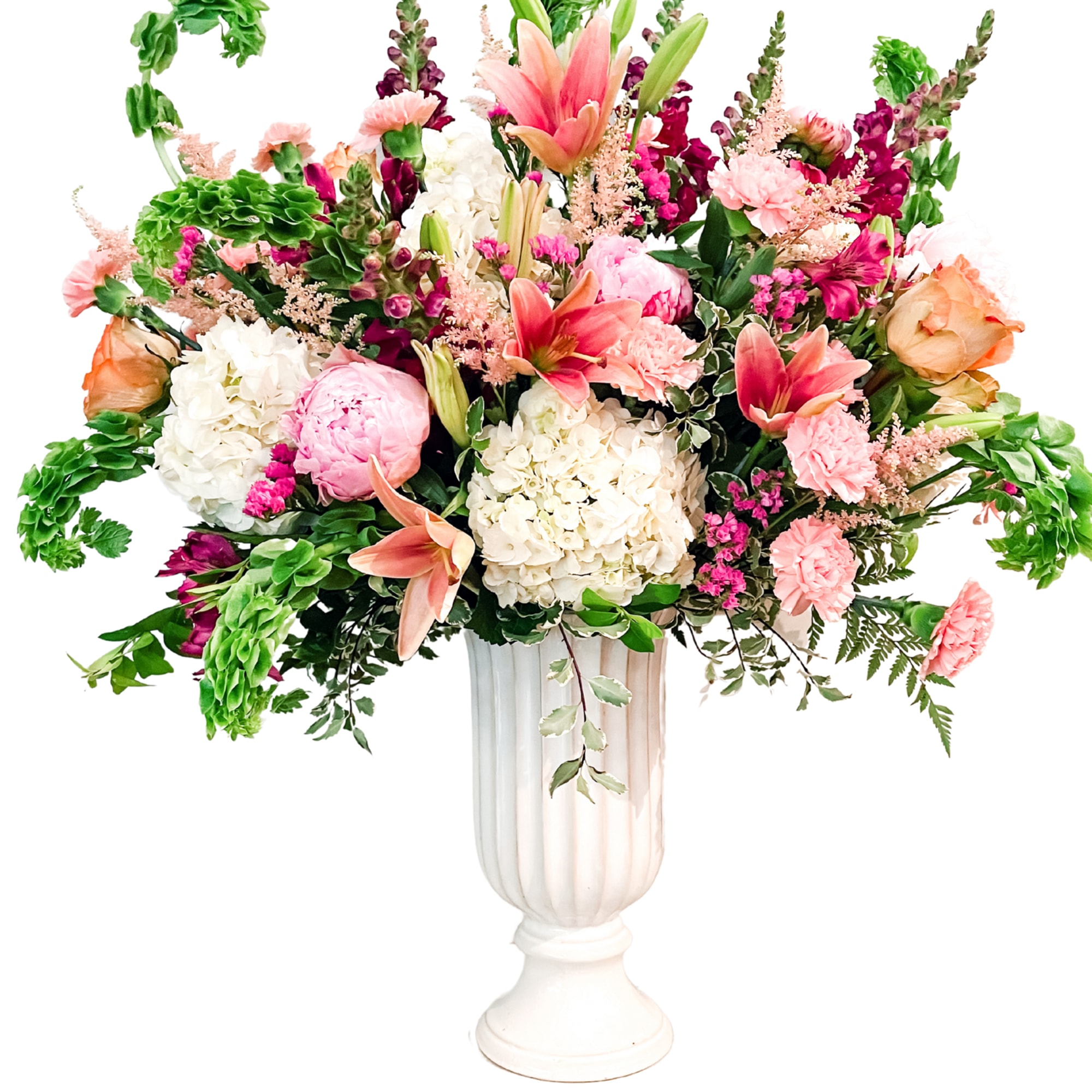 Large mixed flower arrangement in a white pedestal vase