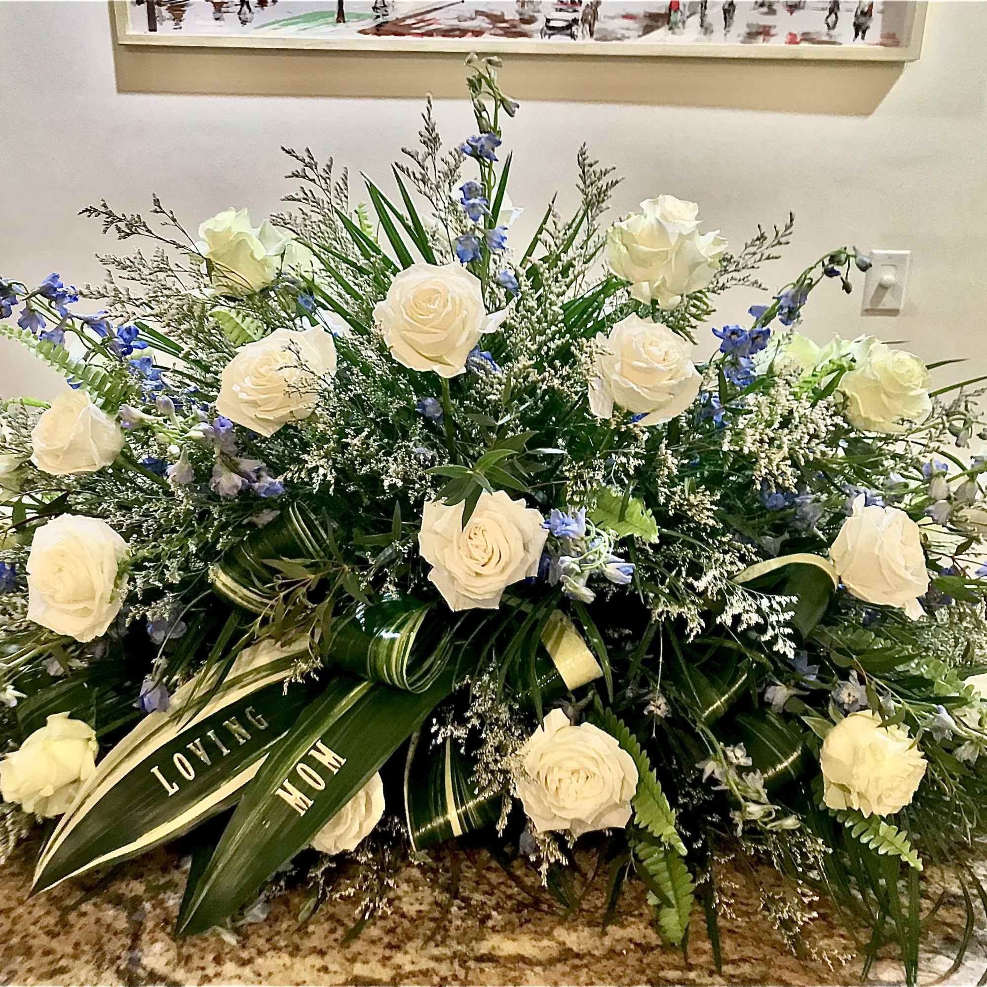 Large white rose spray with blue flowers and a 'Loving Mom' message on leaves