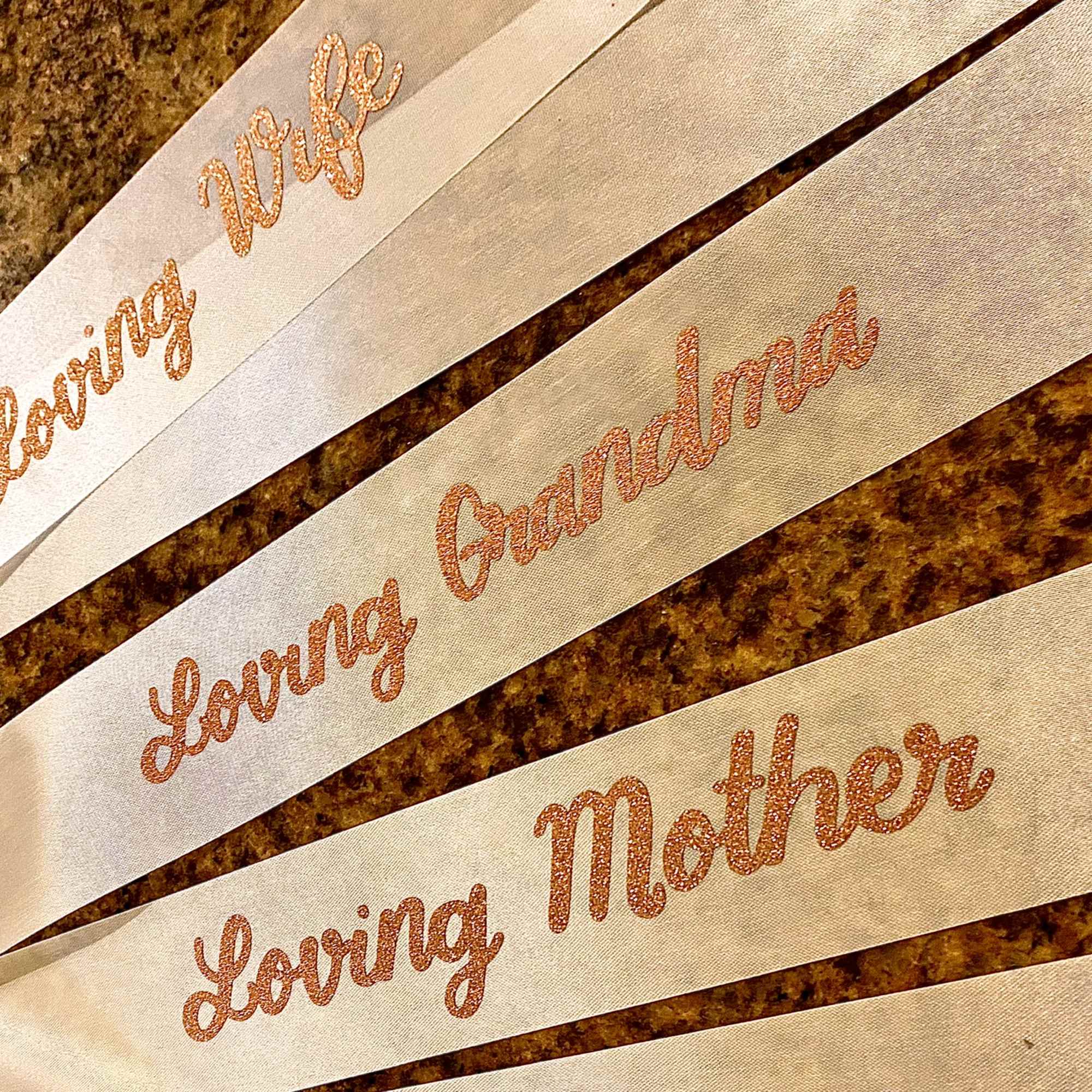 Ivory memorial ribbons reading Loving Wife, Loving Grandma, Loving Mother in glitter script
