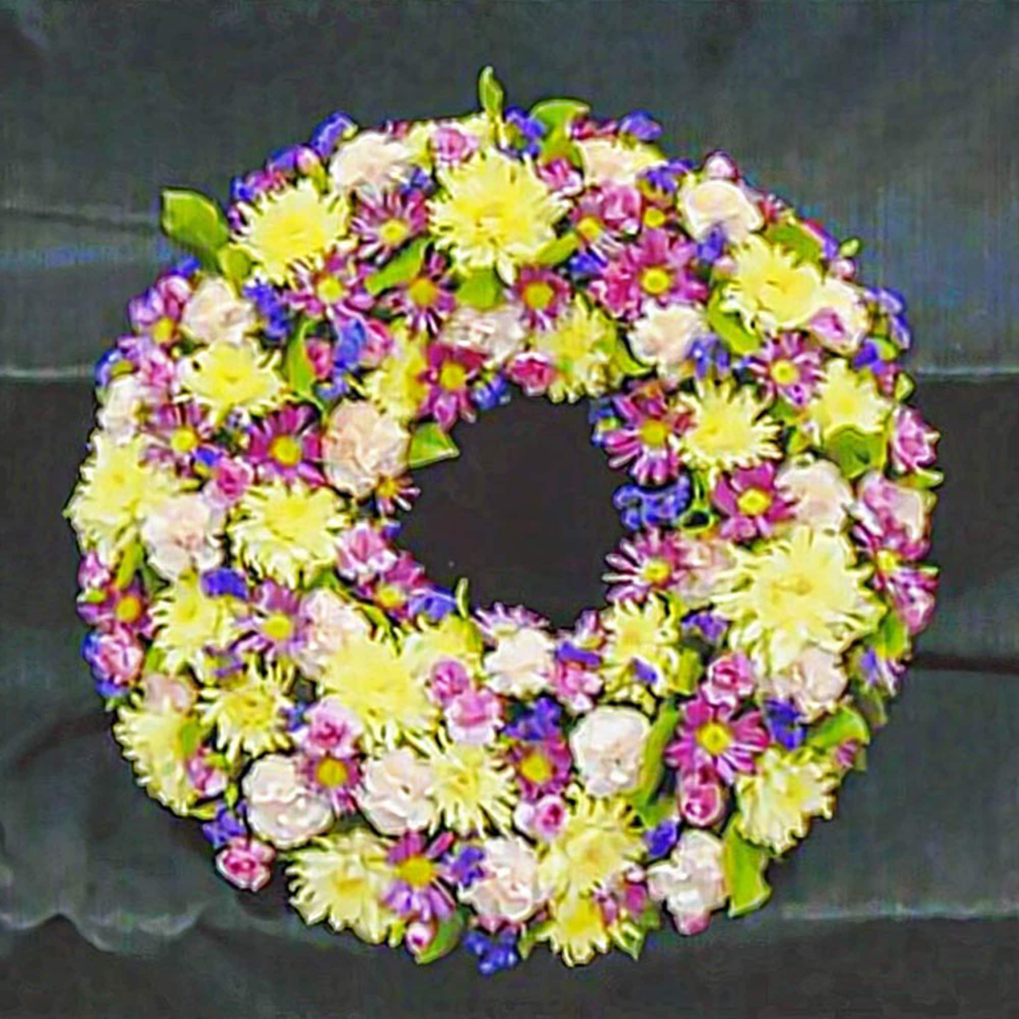 Round wreath of yellow, pink, and purple flowers arranged in a dense ring.