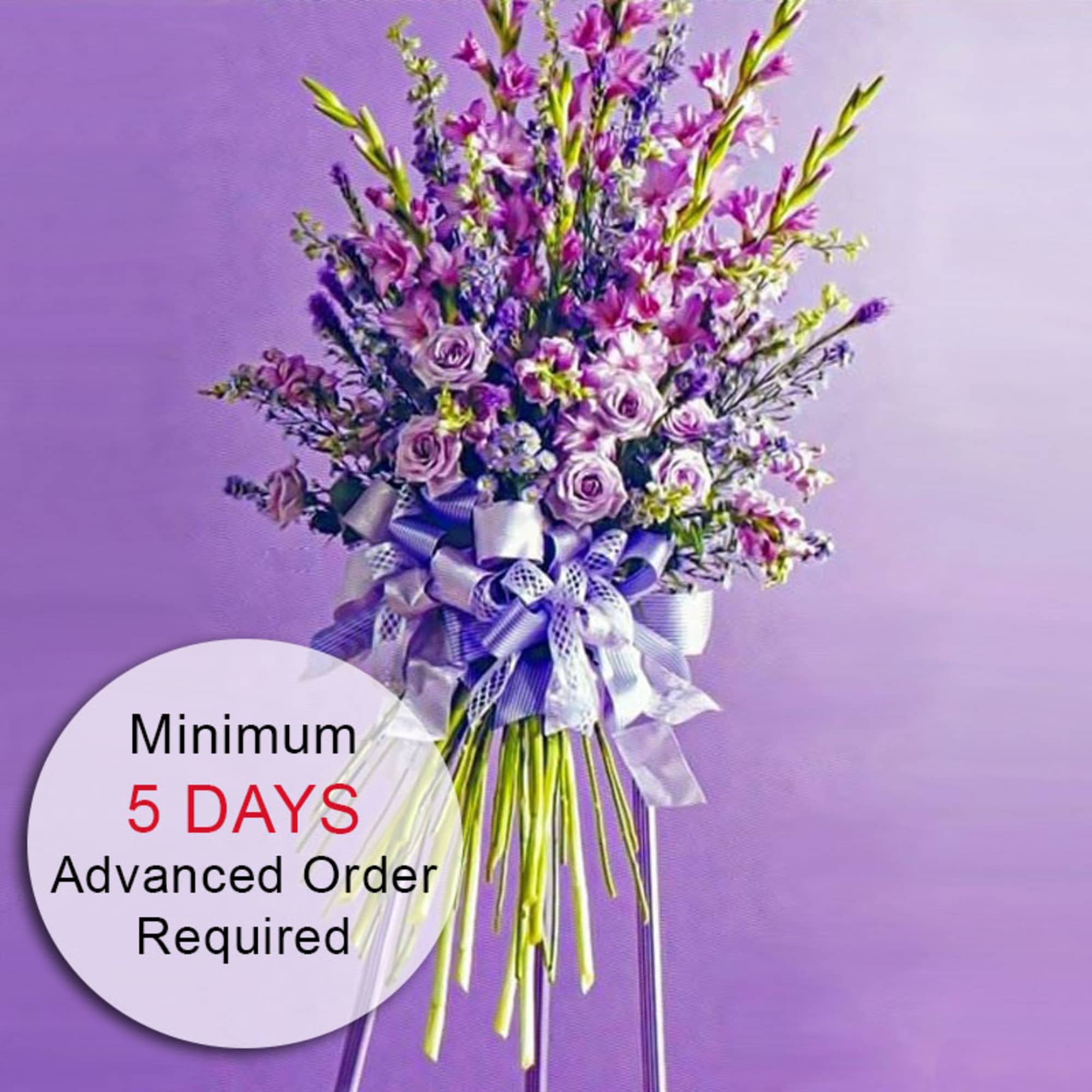 Tall lavender and pink standing flower arrangement with roses and ribbons on a metal stand